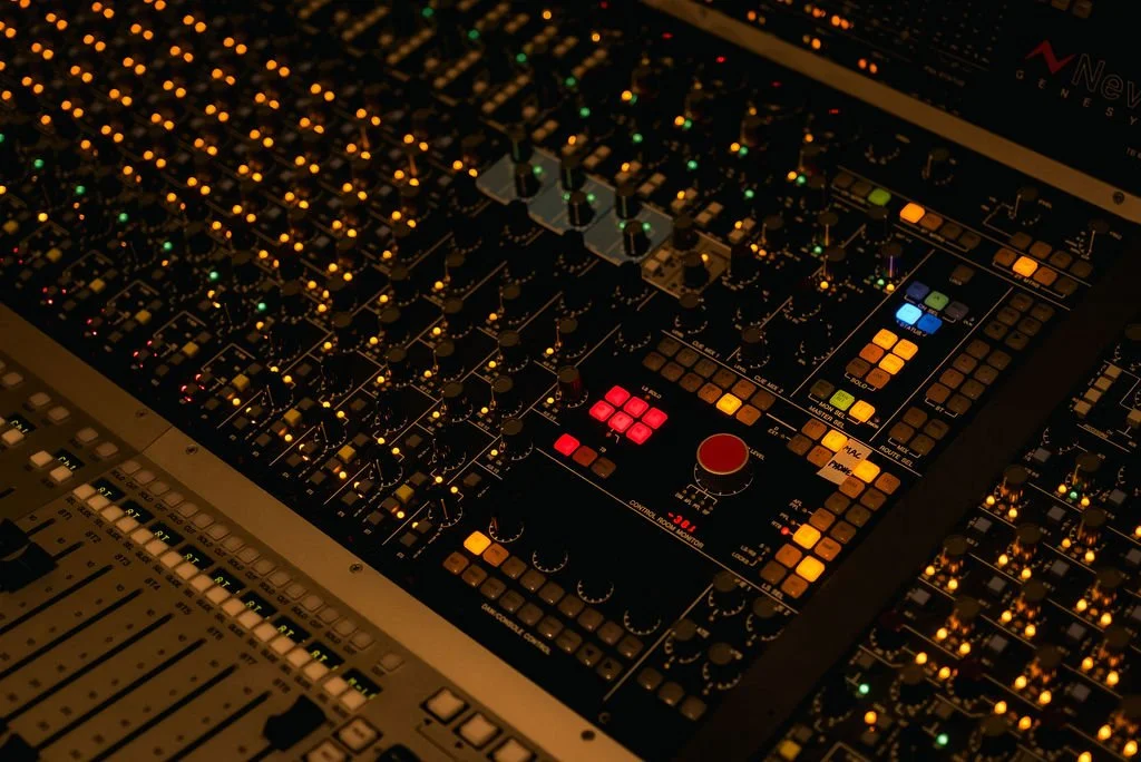 Close-up of an audio mixing console with illuminated buttons and knobs.