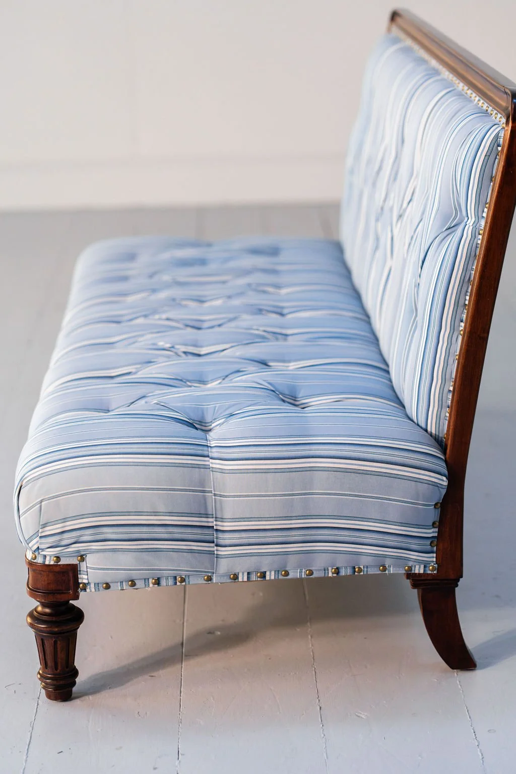 A vintage wooden-framed armchair with a blue and white striped cushioned seat and backrest.