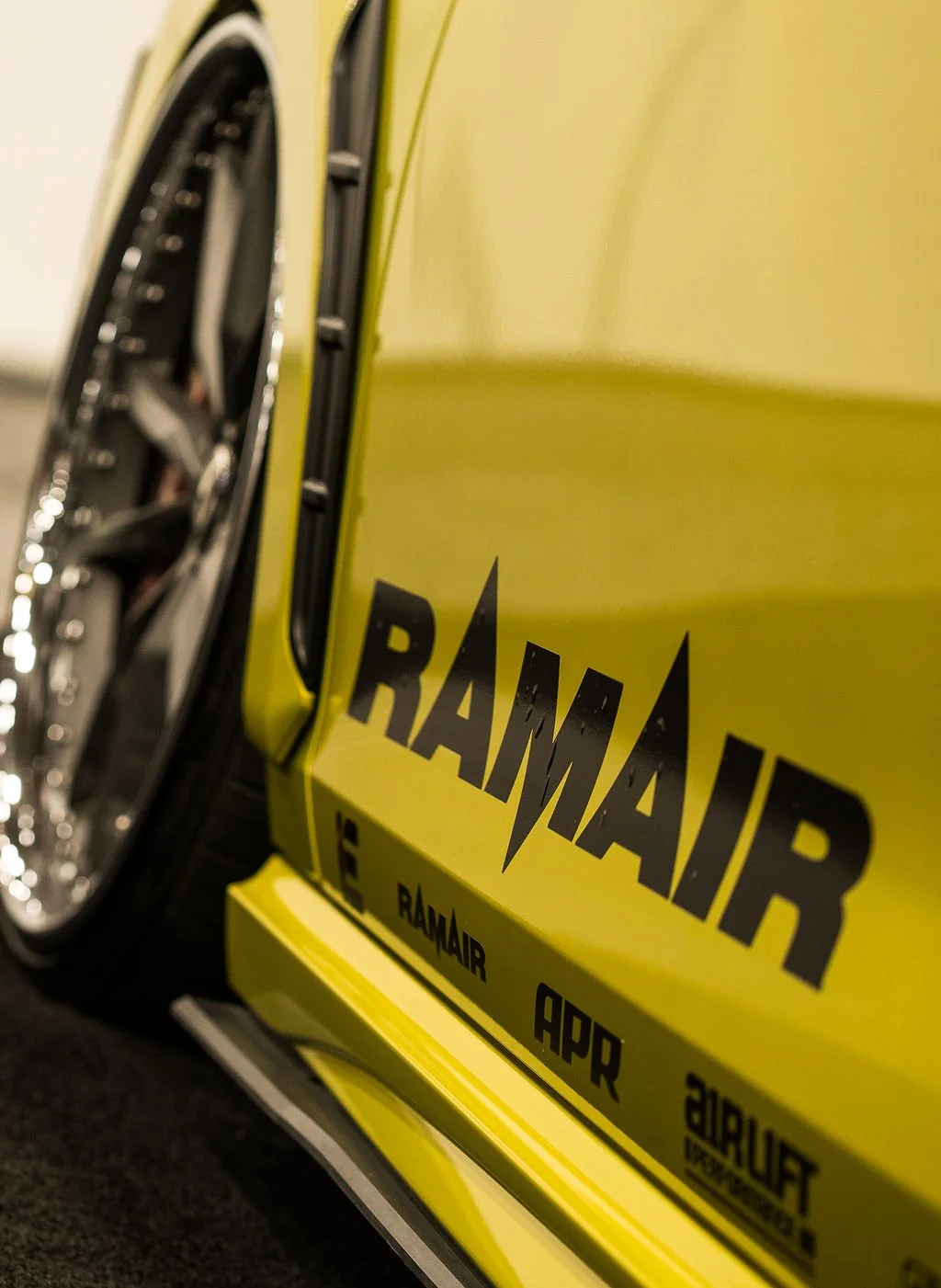 Close-up of a yellow race car with the word 'RAMAIR' printed on the side and the words 'RAMAIR', 'APR', '2020' on the bottom panel.