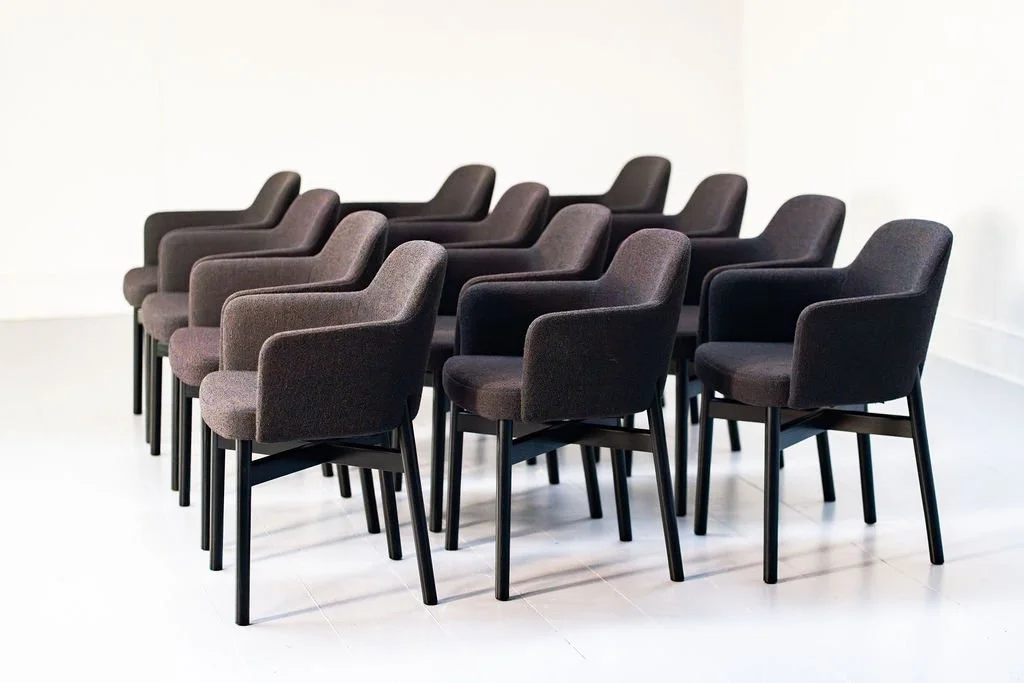 Nine black upholstered chairs arranged in three rows in a white room.