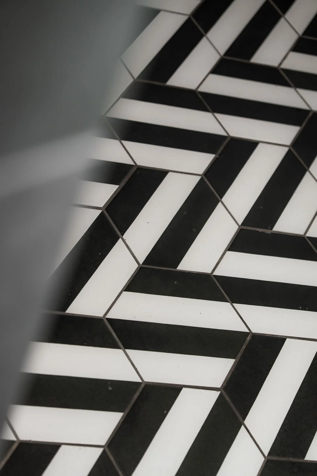 Black and white geometric patterned floor tiles arranged in a herringbone design.