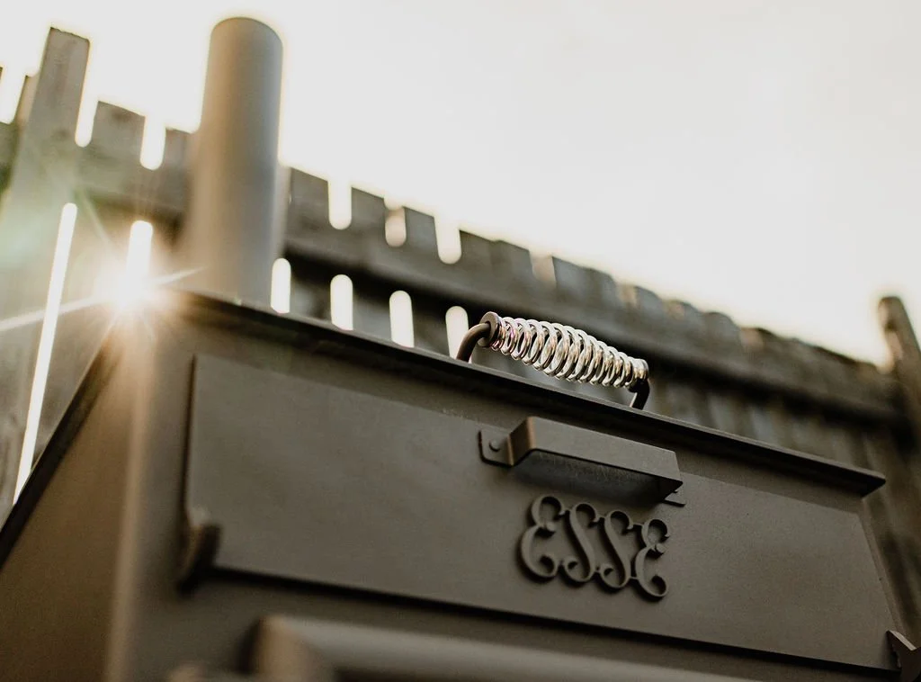 Close-up of a black outdoor stove with sunlight shining on the background.