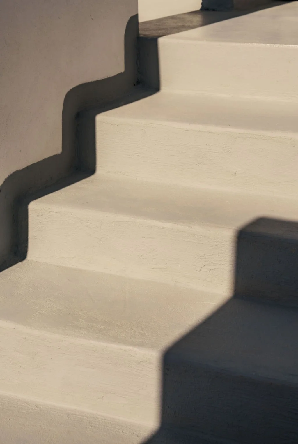 Close-up of white stairs with shadows cast on the steps.