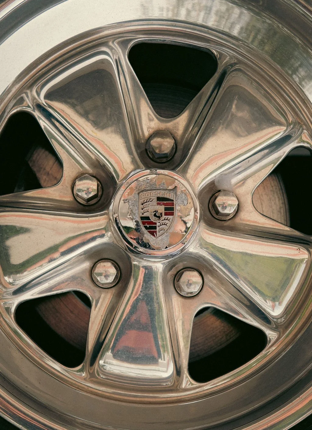 Close-up of a shiny chrome Porsche wheel rim with the Porsche crest in the center.