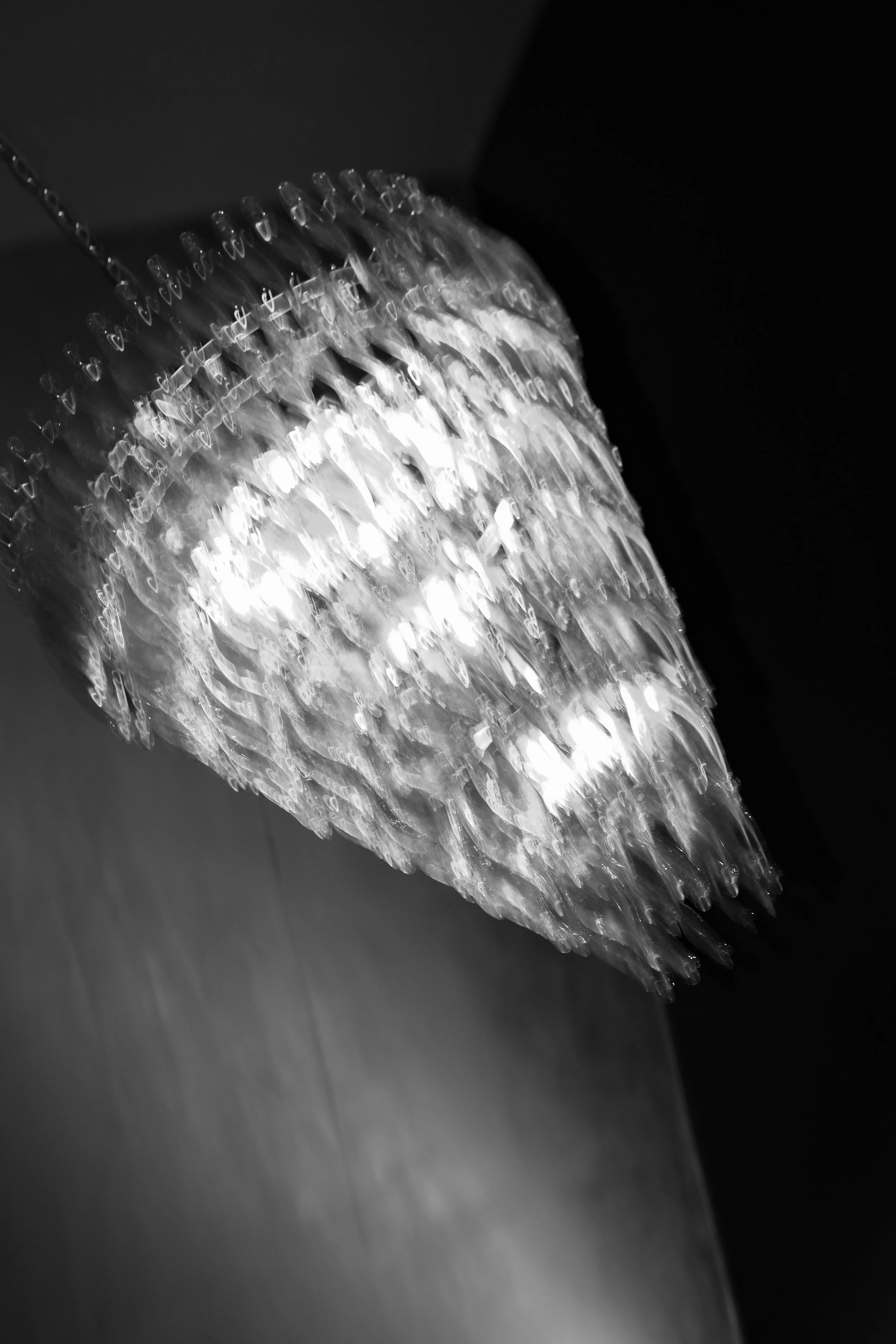 Black and white photo of a large, ornate chandelier hanging from the ceiling.