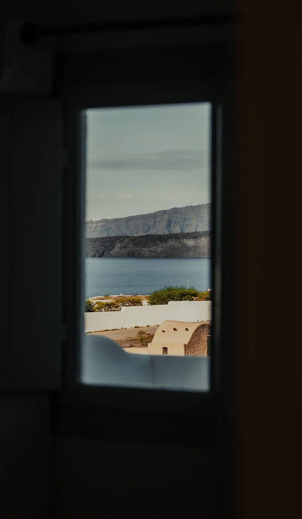 View of mountains, water, and some buildings through a window.