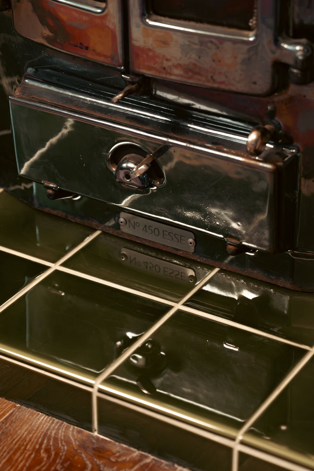 Close-up of vintage industrial machine part with metal label reading 'N° 450 ESSE', reflected in a glossy black surface.