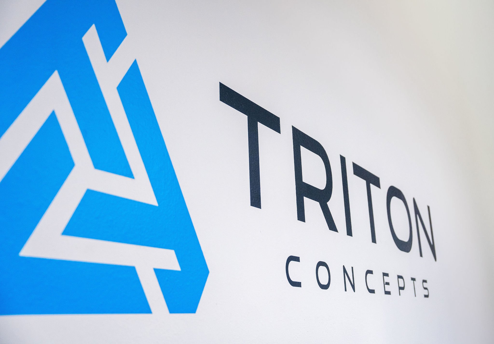 Logo of Triton Concepts featuring a blue geometric star and the words "TRITON CONCEPTS" on a white background.