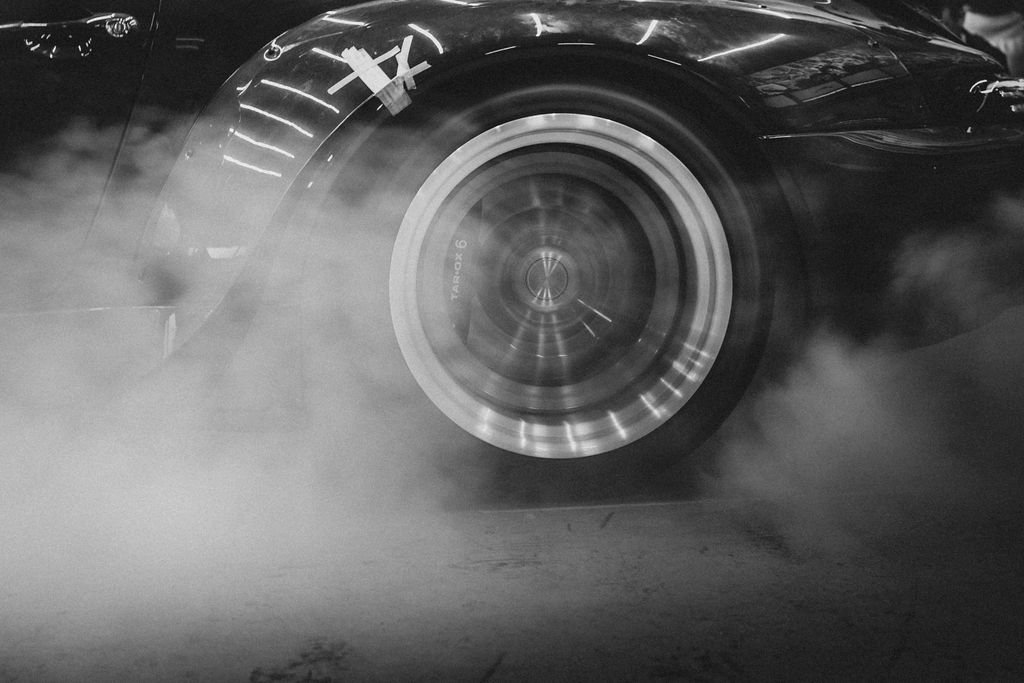 Close-up of a car tire spinning with smoke or tire burnout around it.