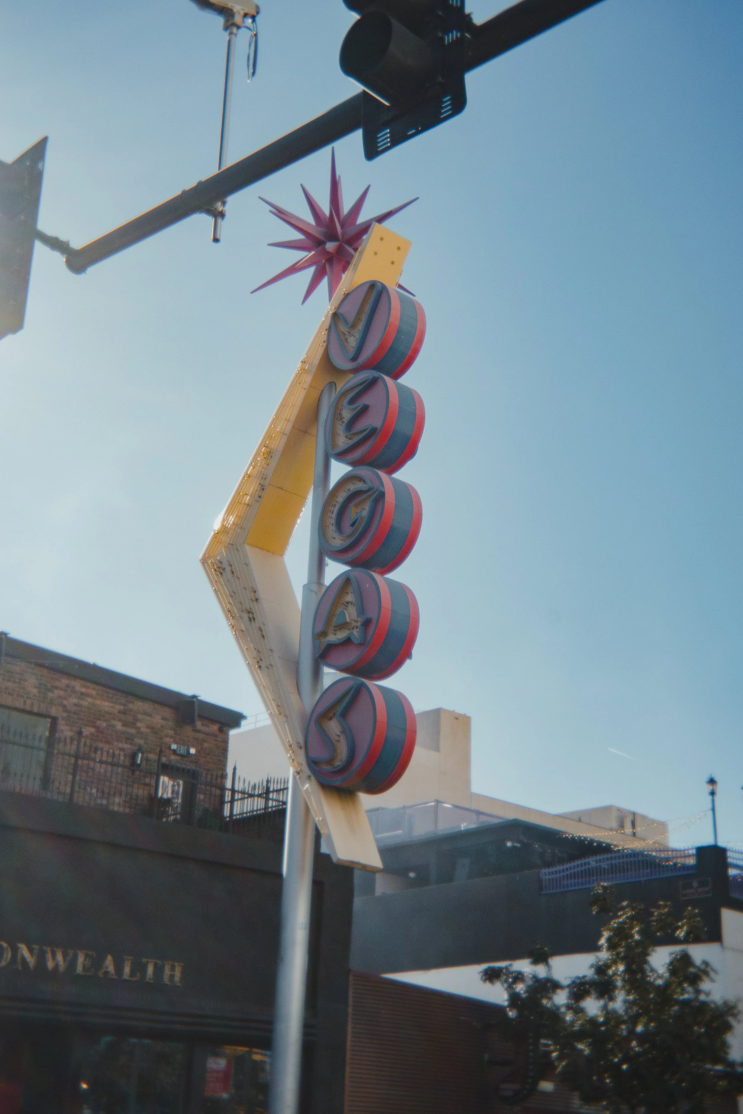 Vintage Vegas sign with neon lights and a starburst at the top against a blue sky.