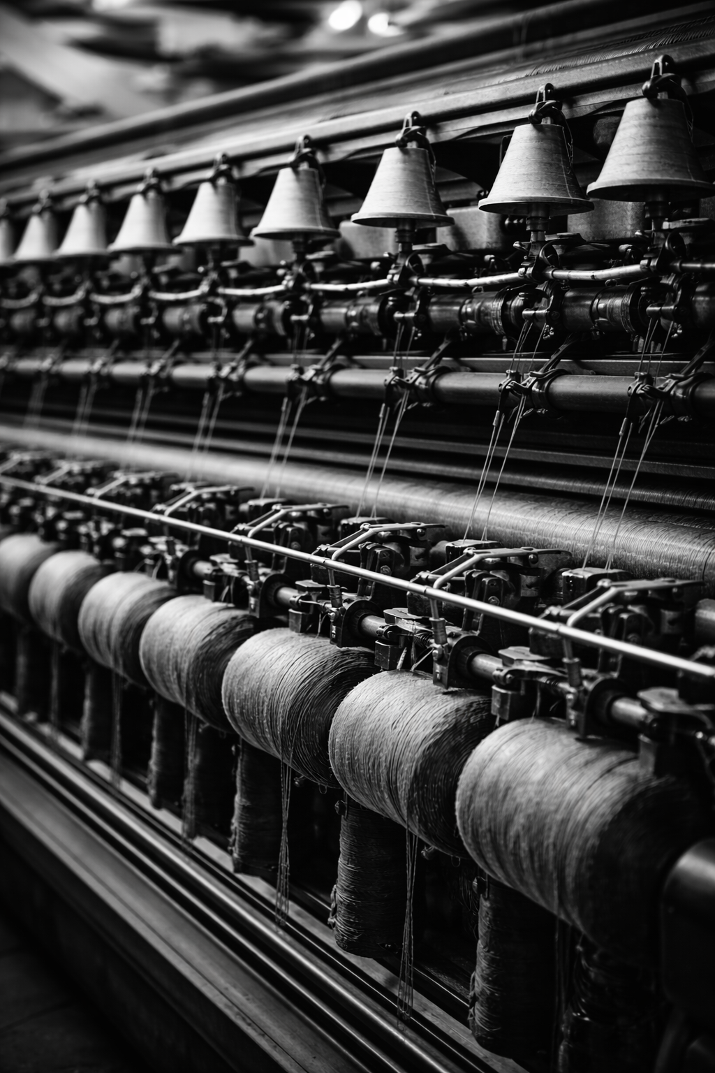 Close-up of vintage industrial textile machine with spools of thread in black and white.