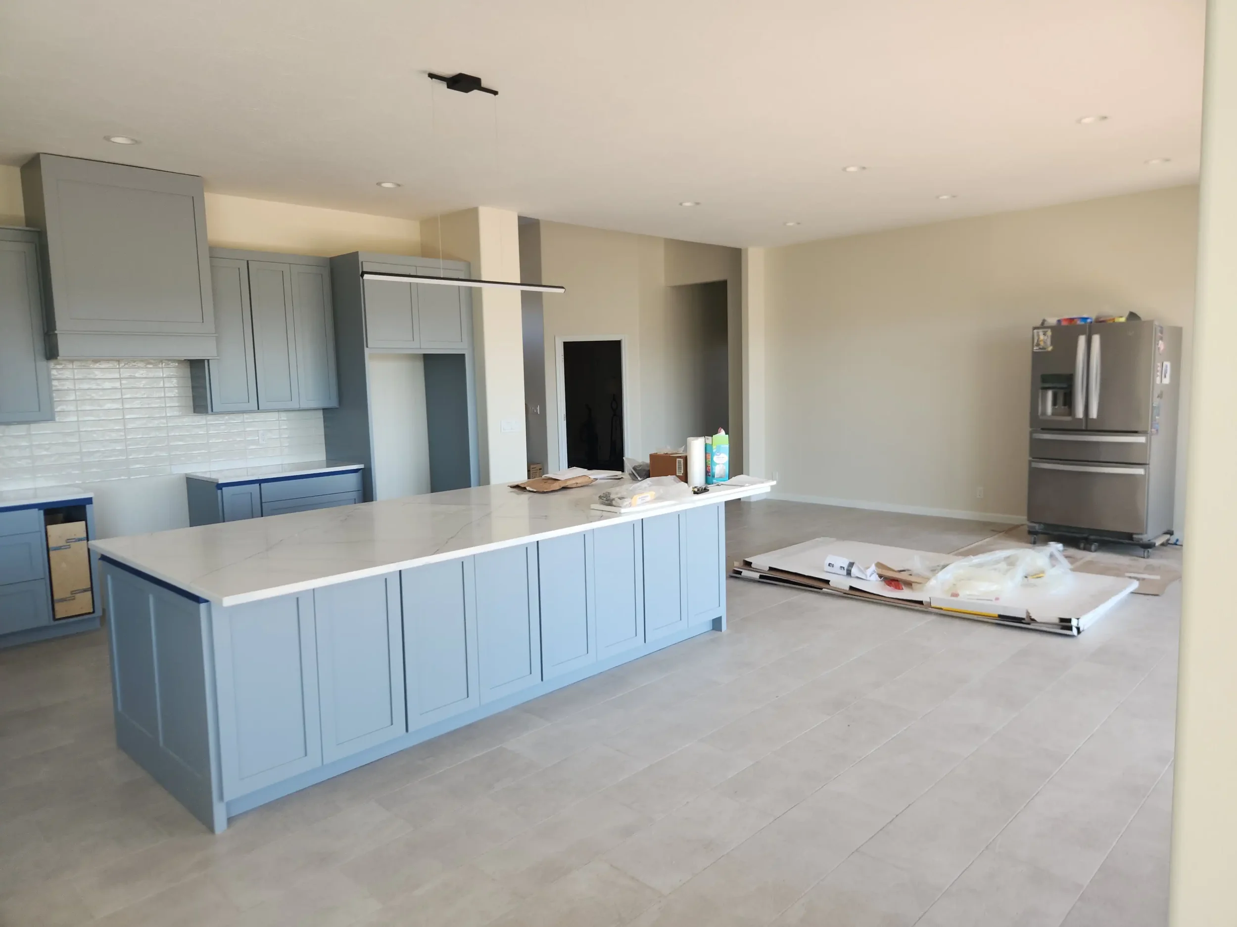 Kitchen remodel by Jepsen Construction with blue cabinets, a large island, quartz countertops, and tile flooring