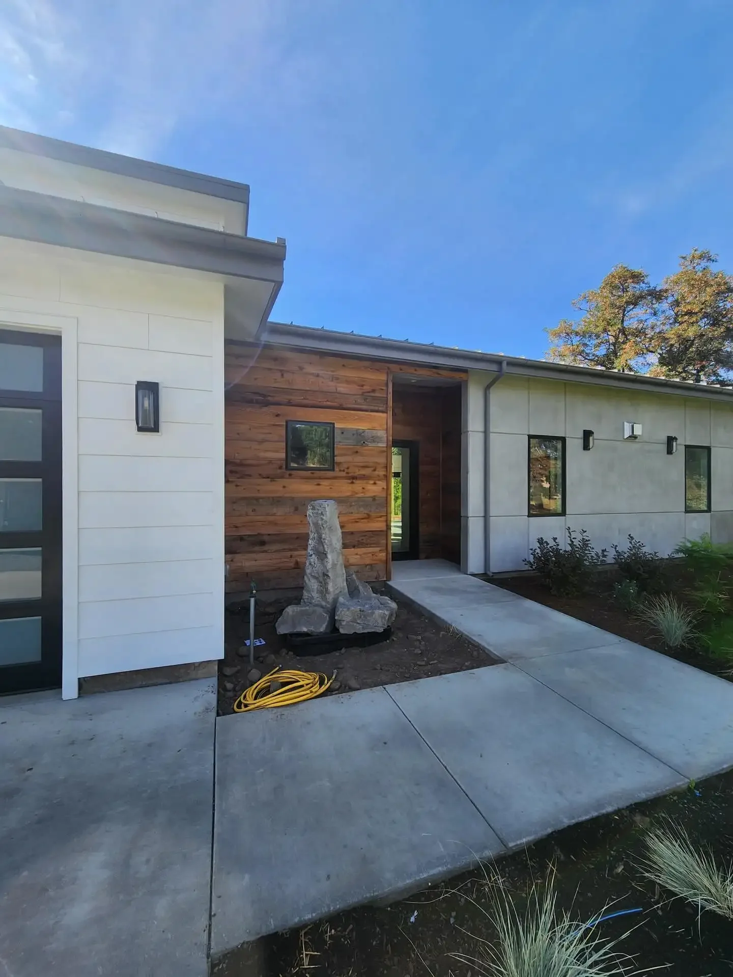 Modern custom home exterior with wood and concrete siding by Jepsen Construction