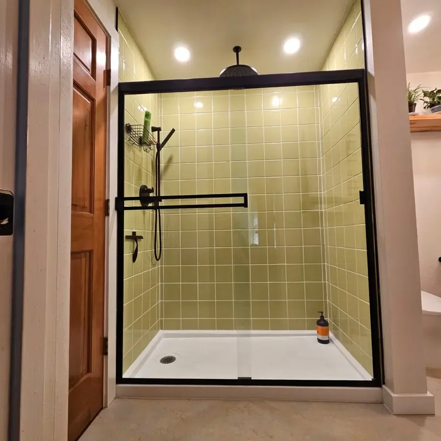 Finished walk-in shower remodel by Jepsen Construction with green tile and black fixtures