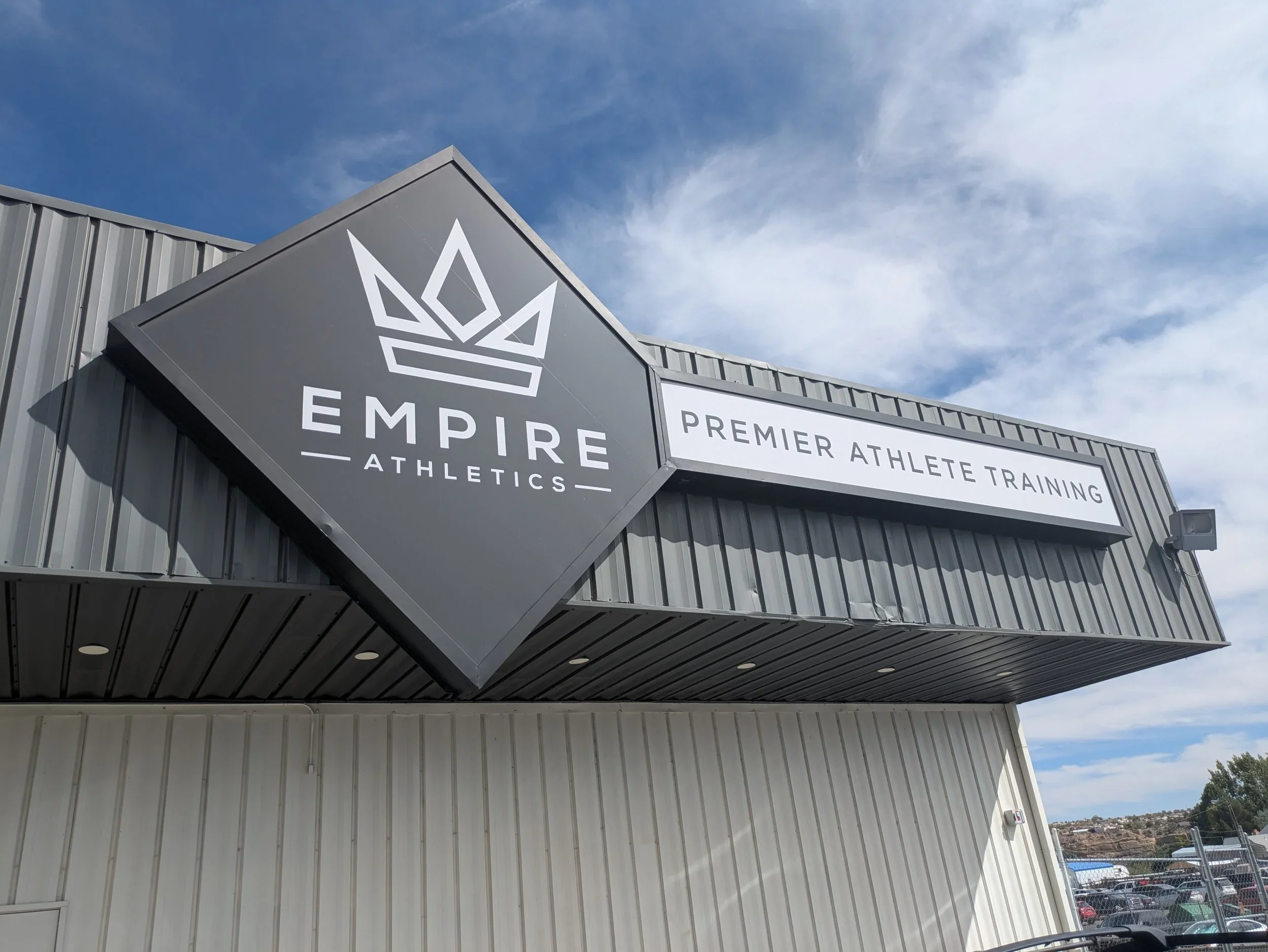 Exterior view of Empire Athletics building with signage indicating premier athlete training, under a partly cloudy sky.