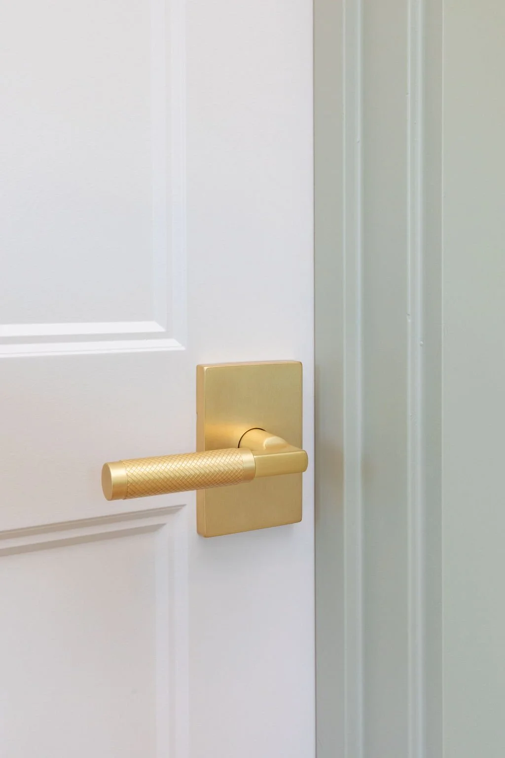 Close-up of a white door with a gold-colored door handle.