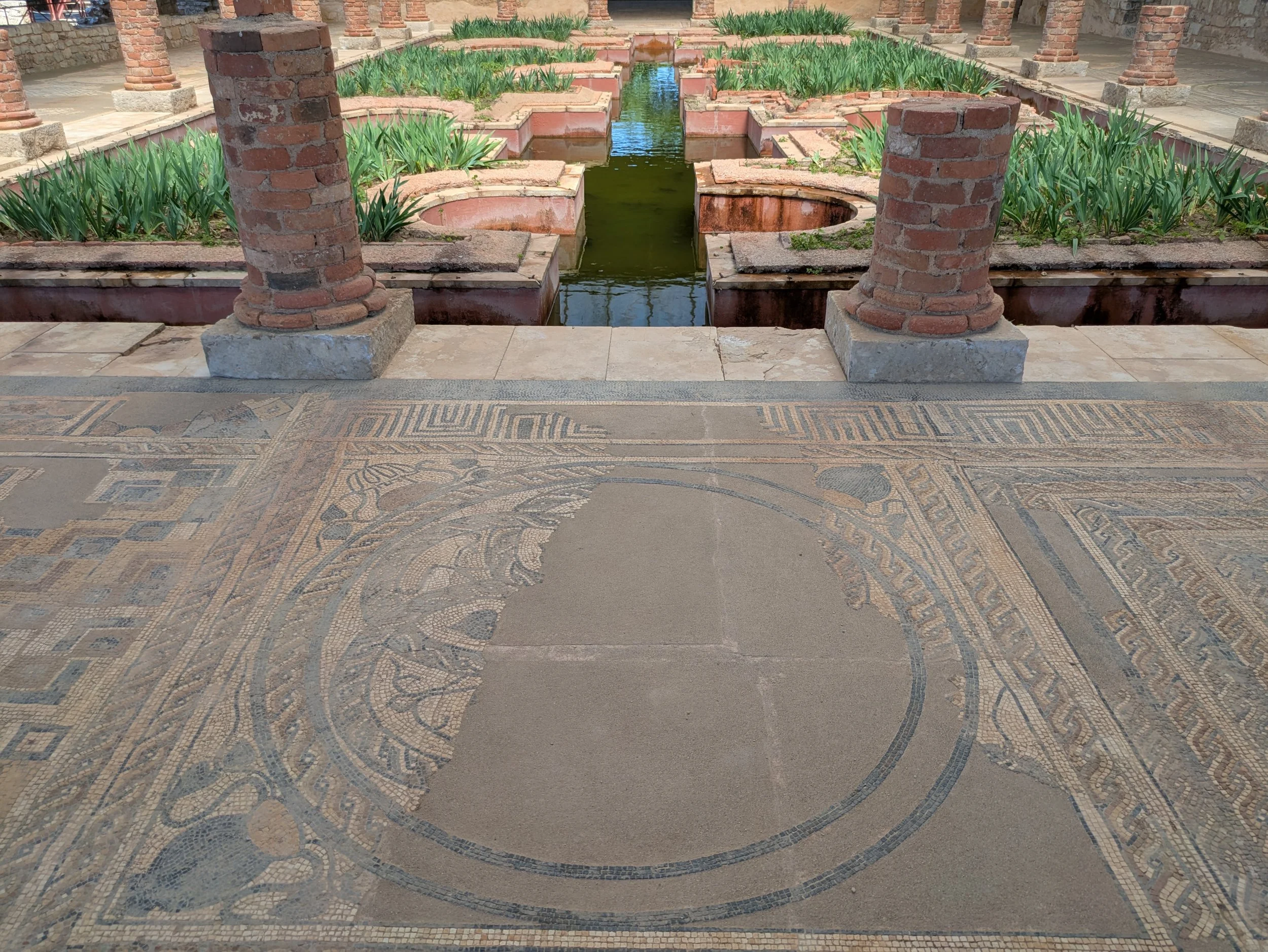 Roman house ruins at conimbriga portugal showing plants and water feature near mosaic tiles