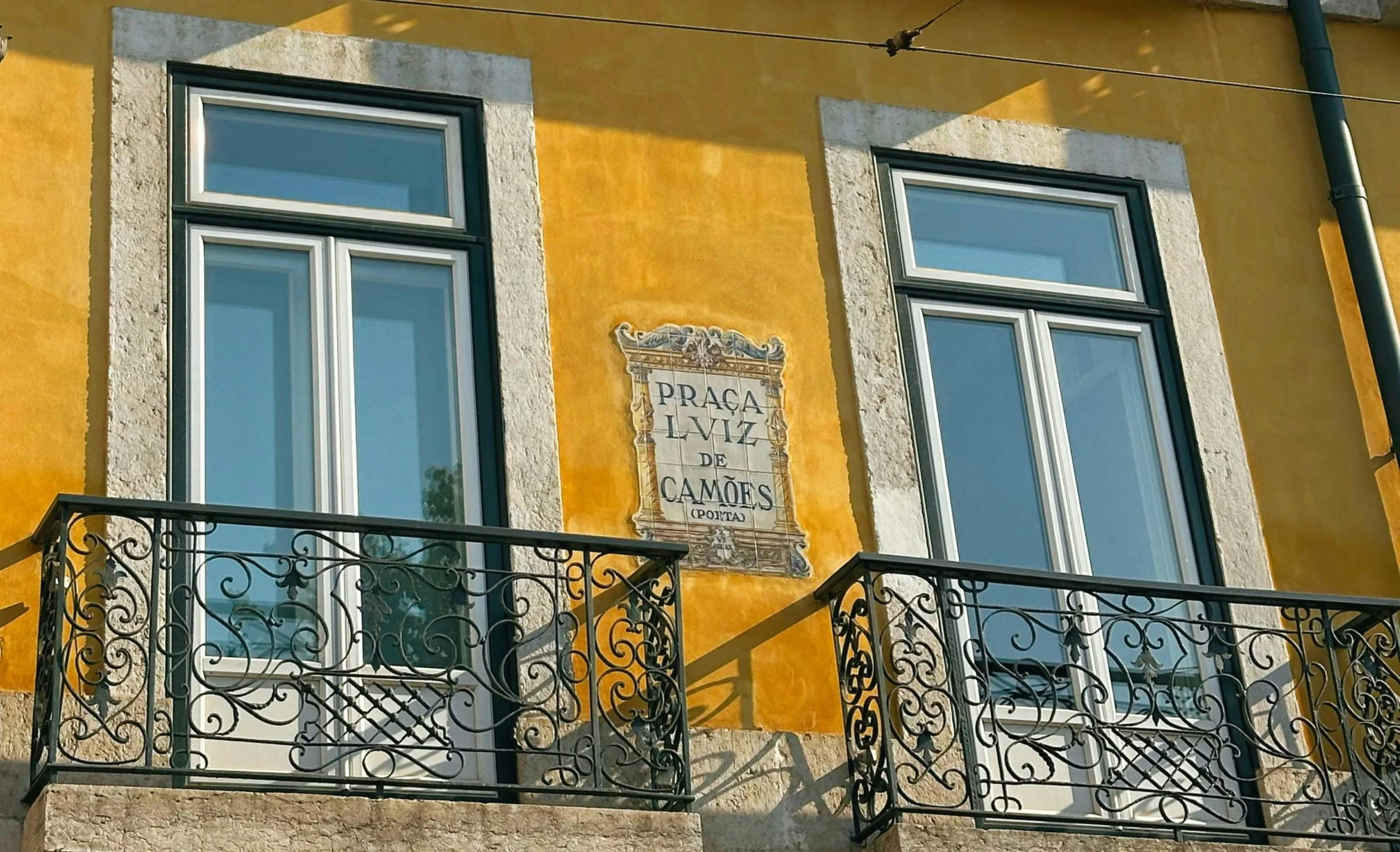 Portuguese building with yellow walls and sign for Praça Luís de Camões