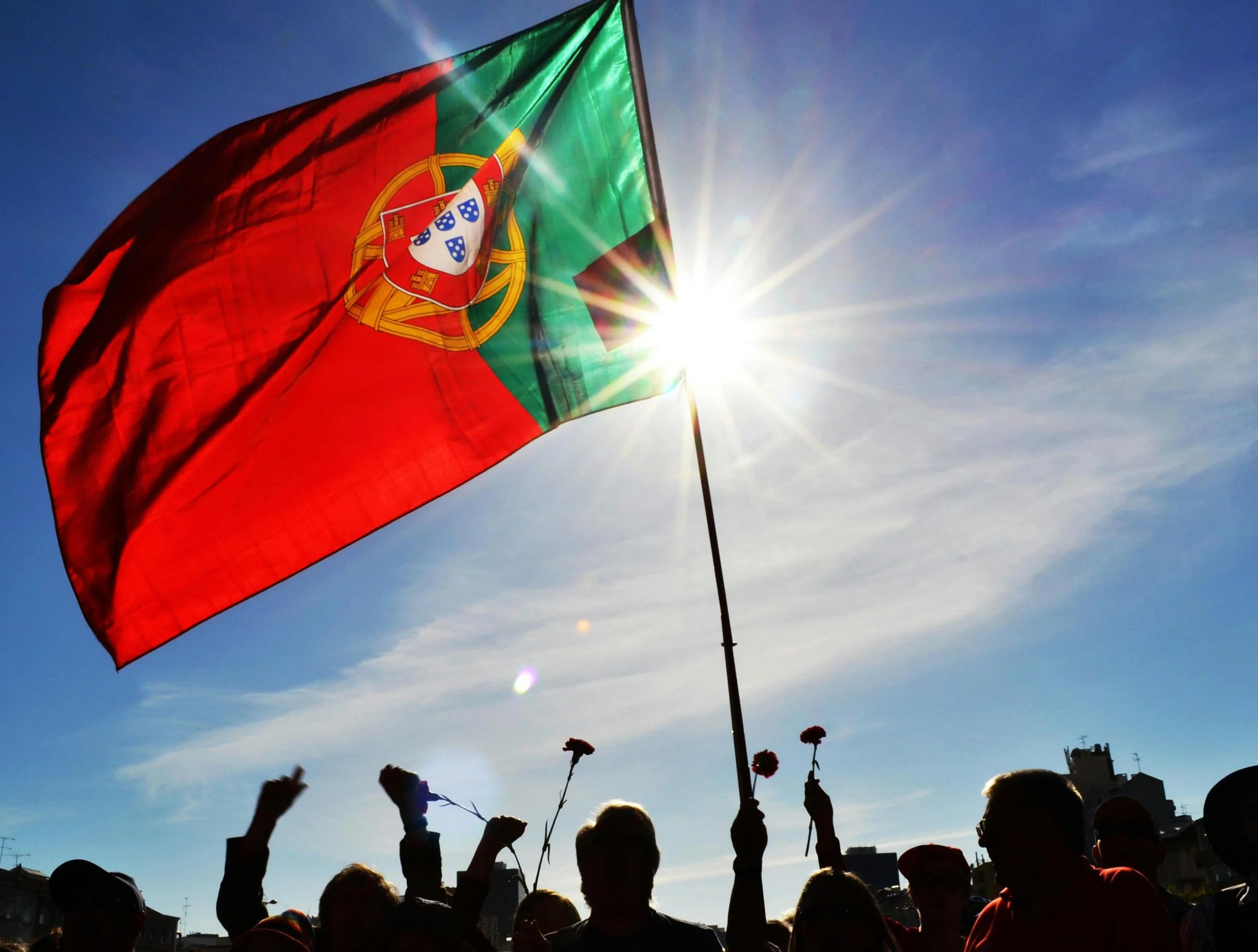 People celebrating Dia de Liberdade in Portugal, waving Portuguese flag and holding red Carnations - the carnation revolution