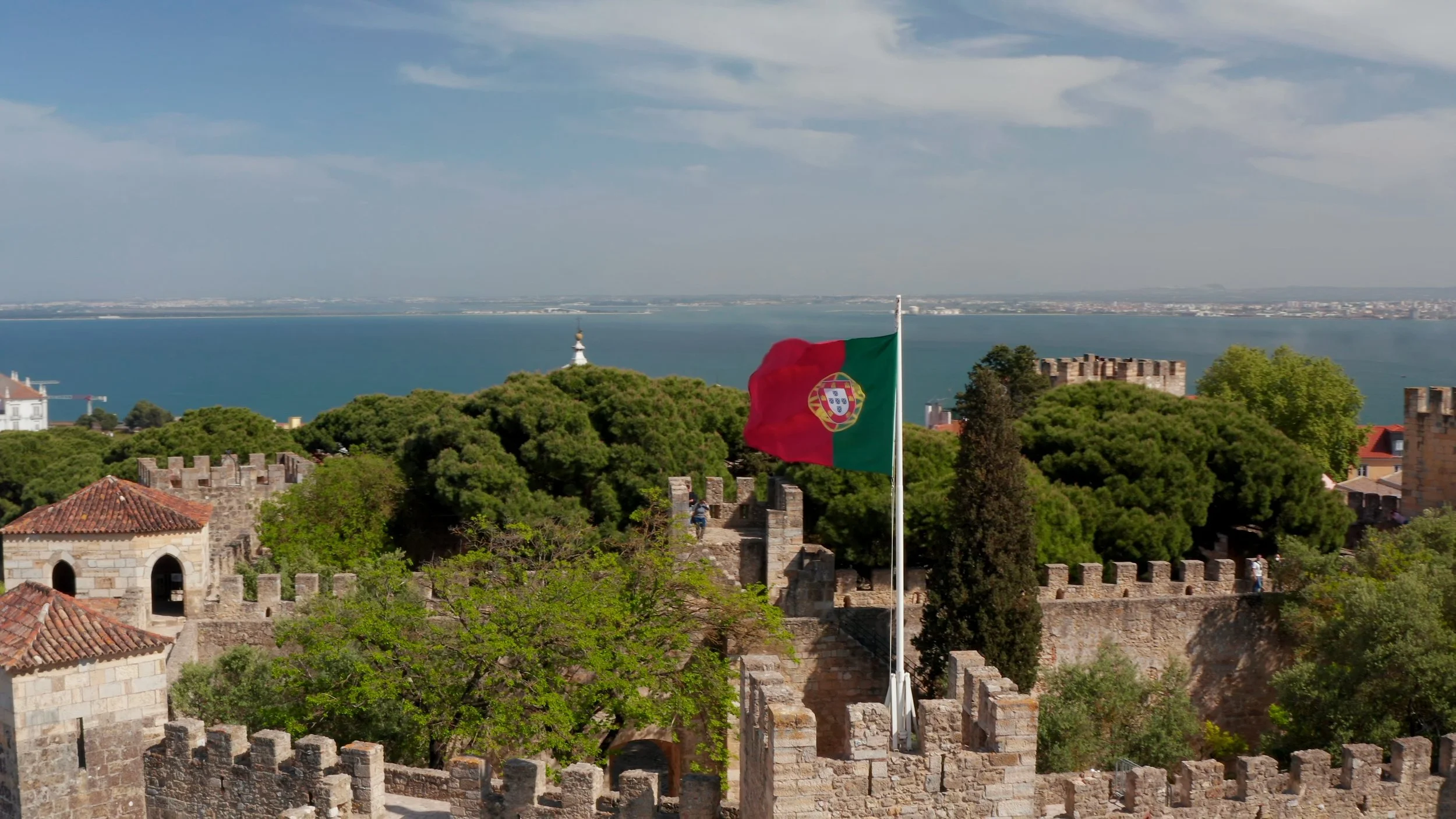 flag of Portugal flying atop the castle walls in Lisbon along the Tegus river