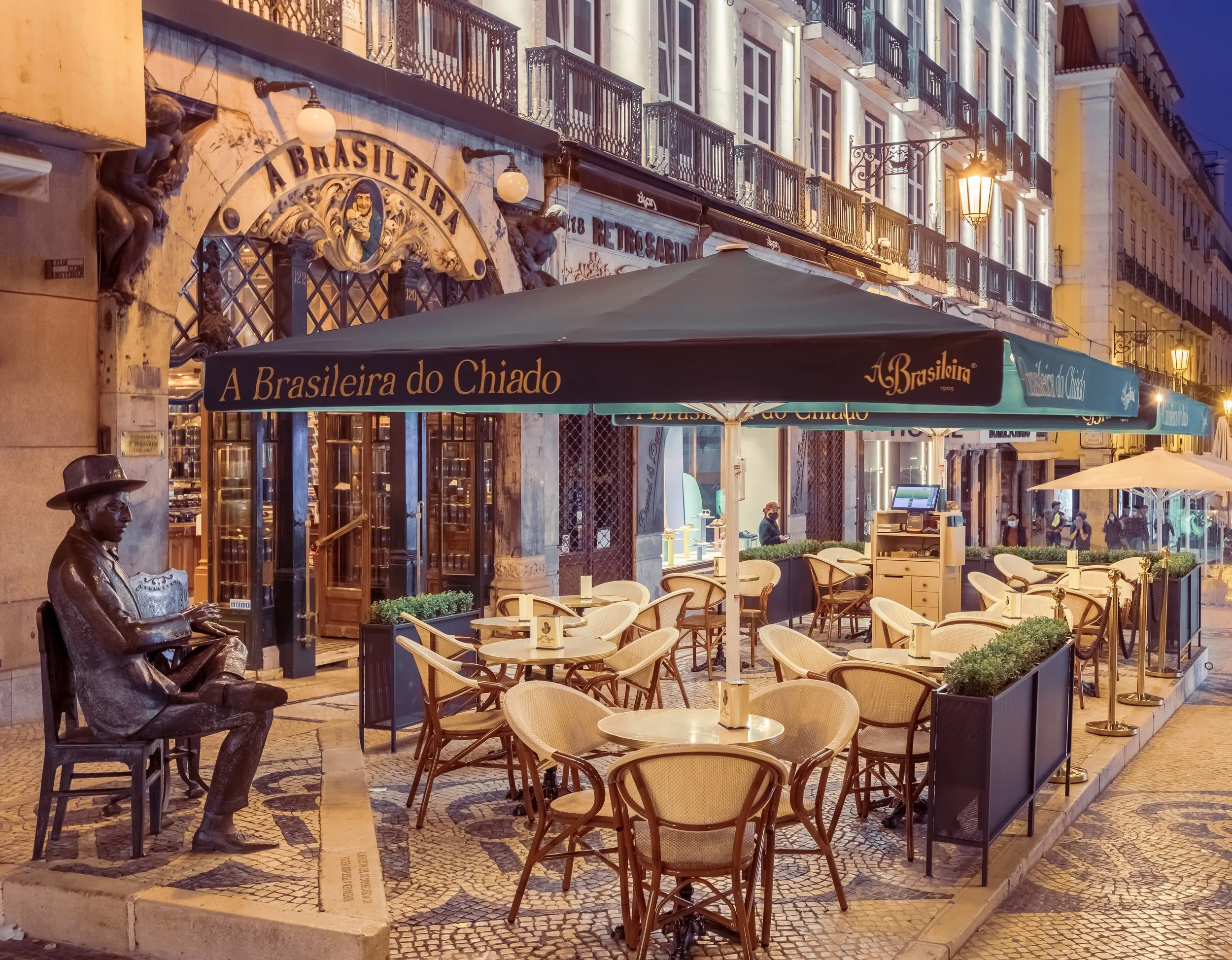 Photo of the outside of A Brasiliera do Chiado café in Lisbon, Portugal with statue of Fernando Pessoa.