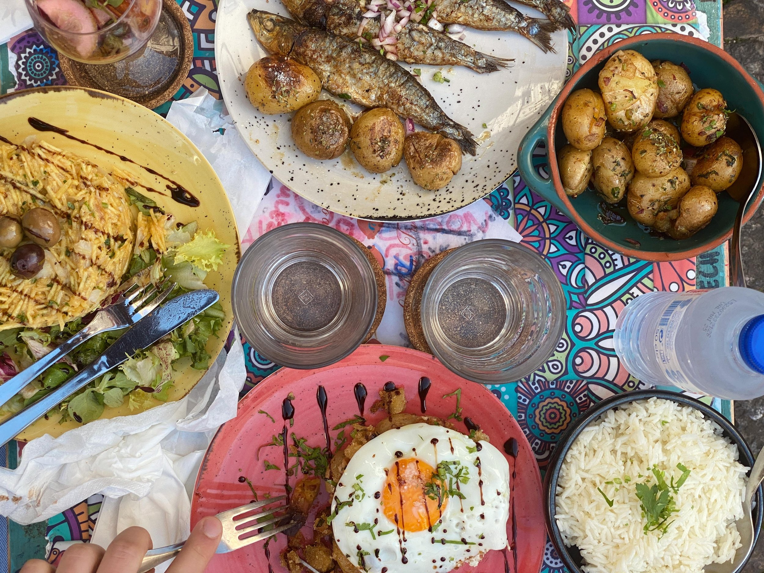 Portuguese family dinner with sardines, potatoes, bacalhau a bras, egg, wine