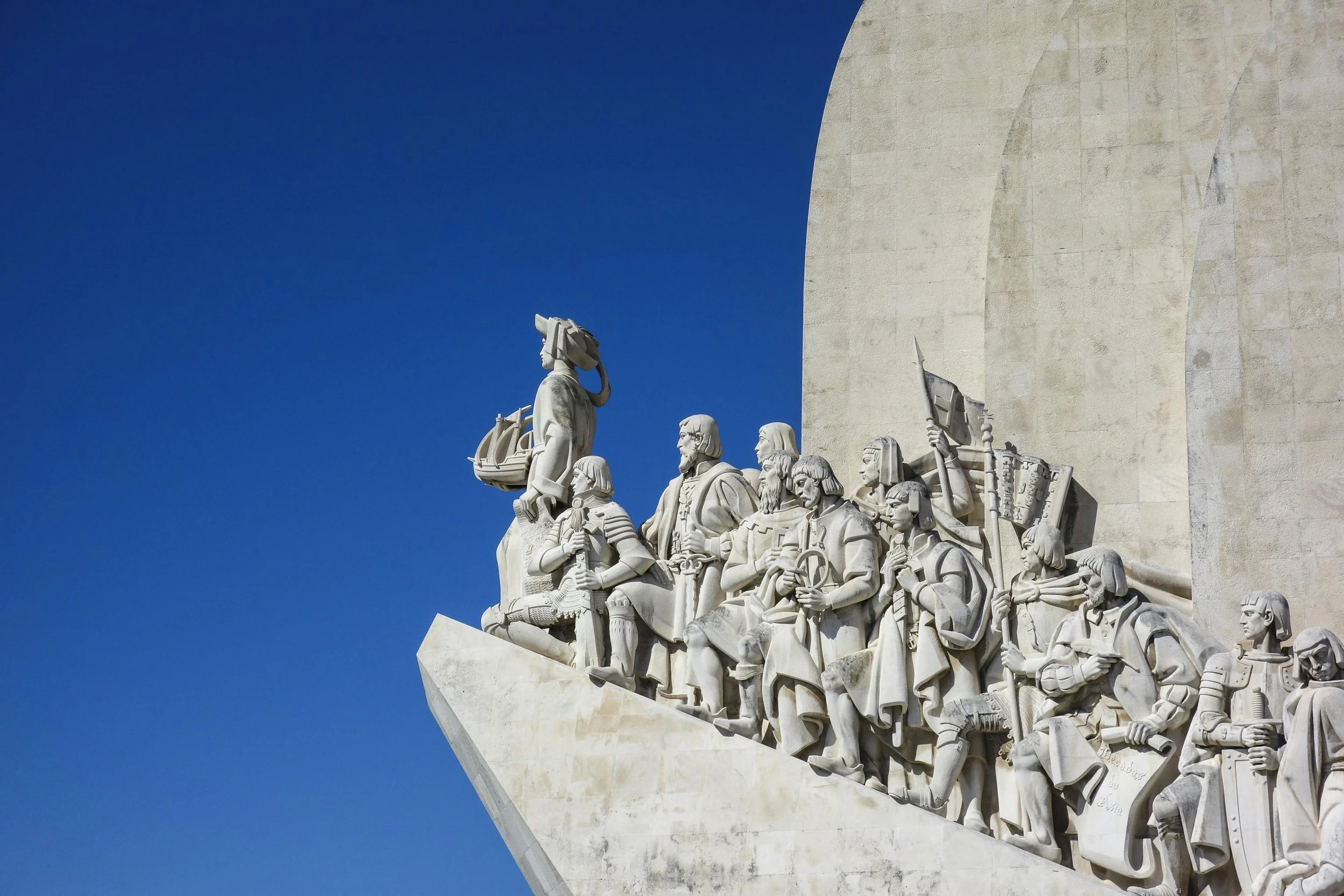 Statue of historical figures on a building facade against a clear blue sky.