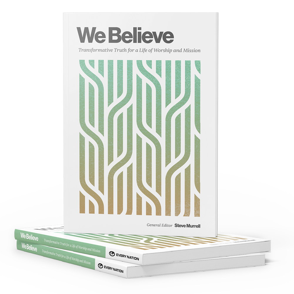 Three copies of a book titled 'We Believe' with a white cover and a stylized tree design in shades of green and gold. The book's subtitle is 'Transformative Truth for a Life of Worship and Mission,' and the general editor is Steve Murrell. Two copies are stacked flat on a surface, and one copy is standing upright behind them.