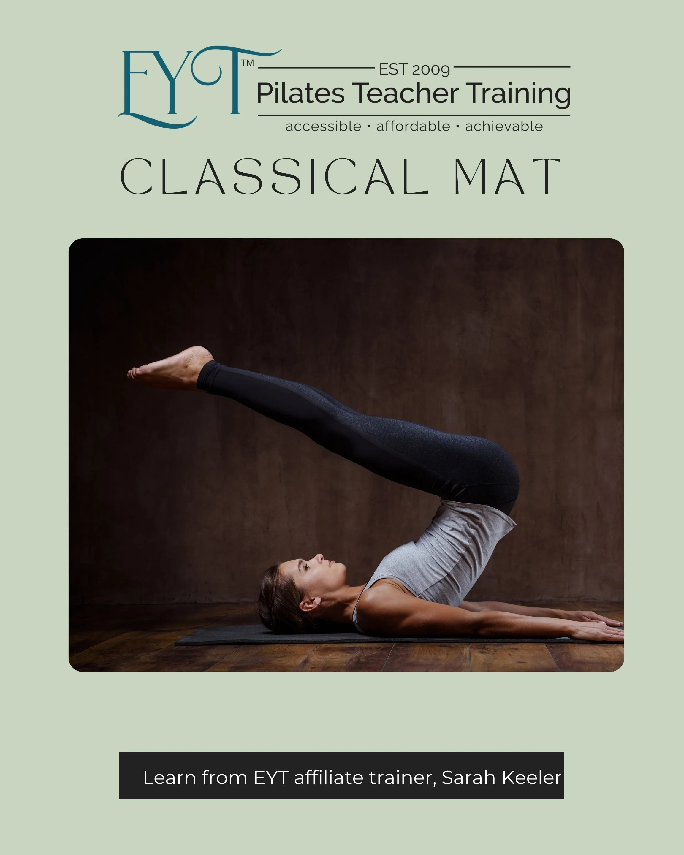 A woman practicing Pilates indoors, lying on her back with one leg extended upward and hands supporting her leg, on a black yoga mat during a Pilates certification in Rochester NY.