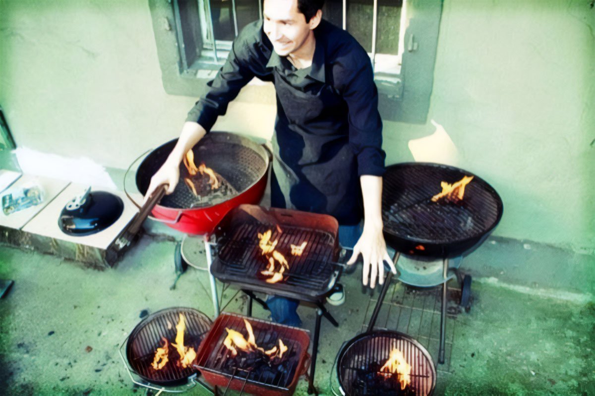 Art Title - Too many Kitchens in the Cook, Merlin Zuni, photo of Merlin Zuni surrounded by flaming BBQs.