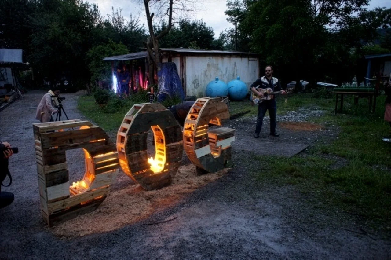 Art Title - Hotdog, Merlin Zuni, photo of Larry Bang Bang playing a "Fire Melody" during the fire lighting of sculpture