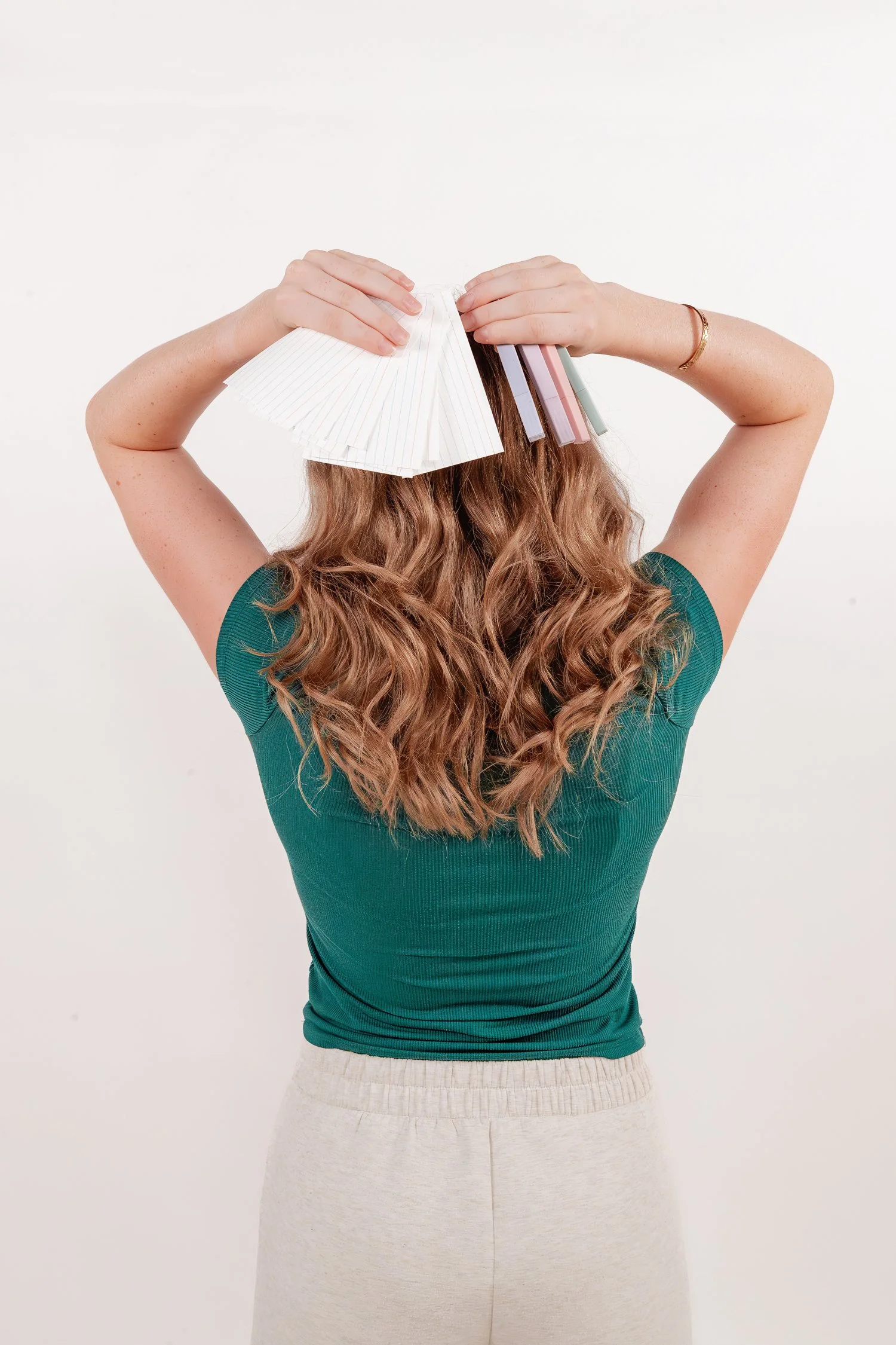 Adelyn holding a fan of blank index cards and pastel highlighters behind her head in the studio