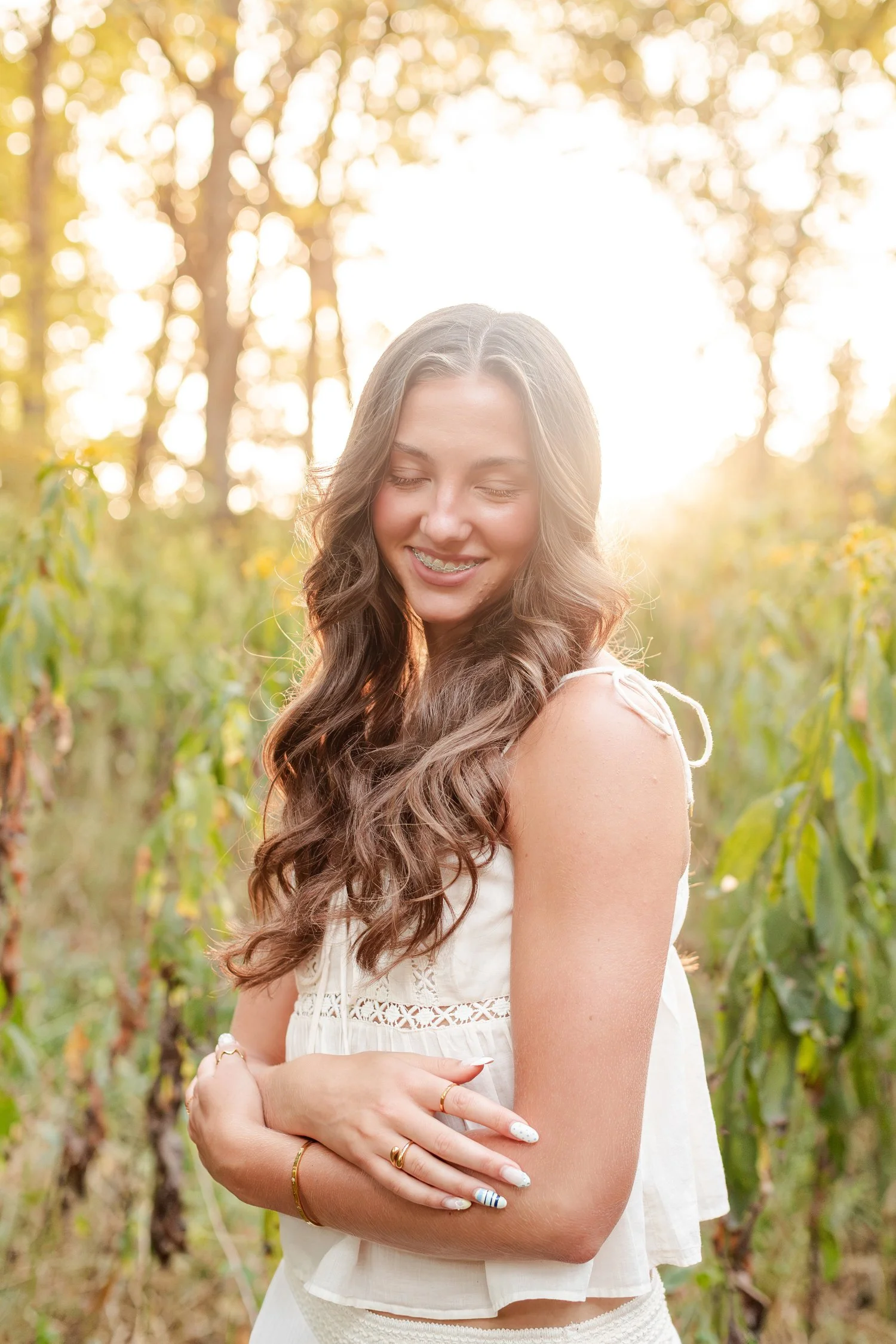 Eisley smiling in tall grass at golden hour, river senior pictures near Bolivar, MO