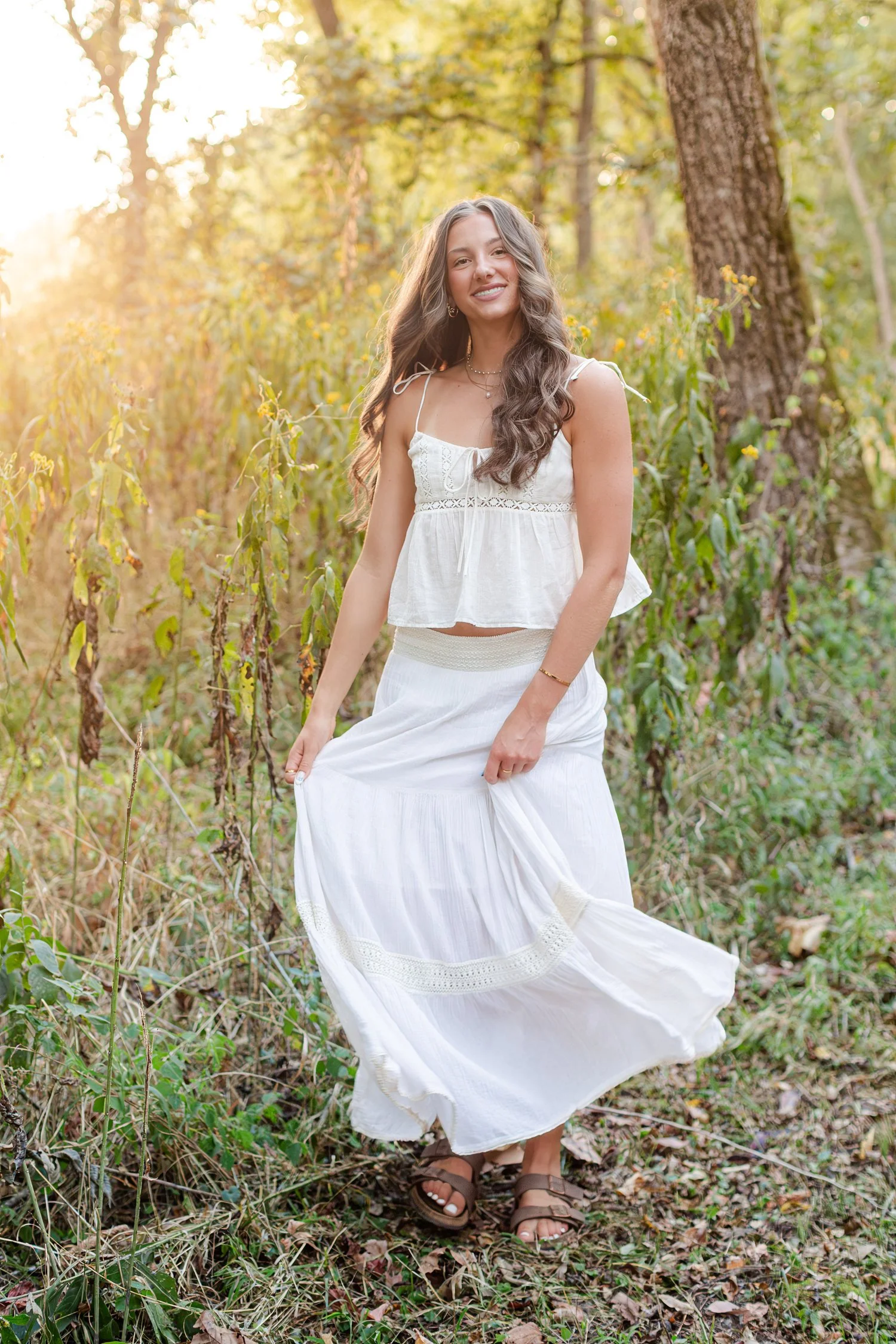 Eisley twirling her white skirt in tall grass, senior pictures near Bolivar, MO