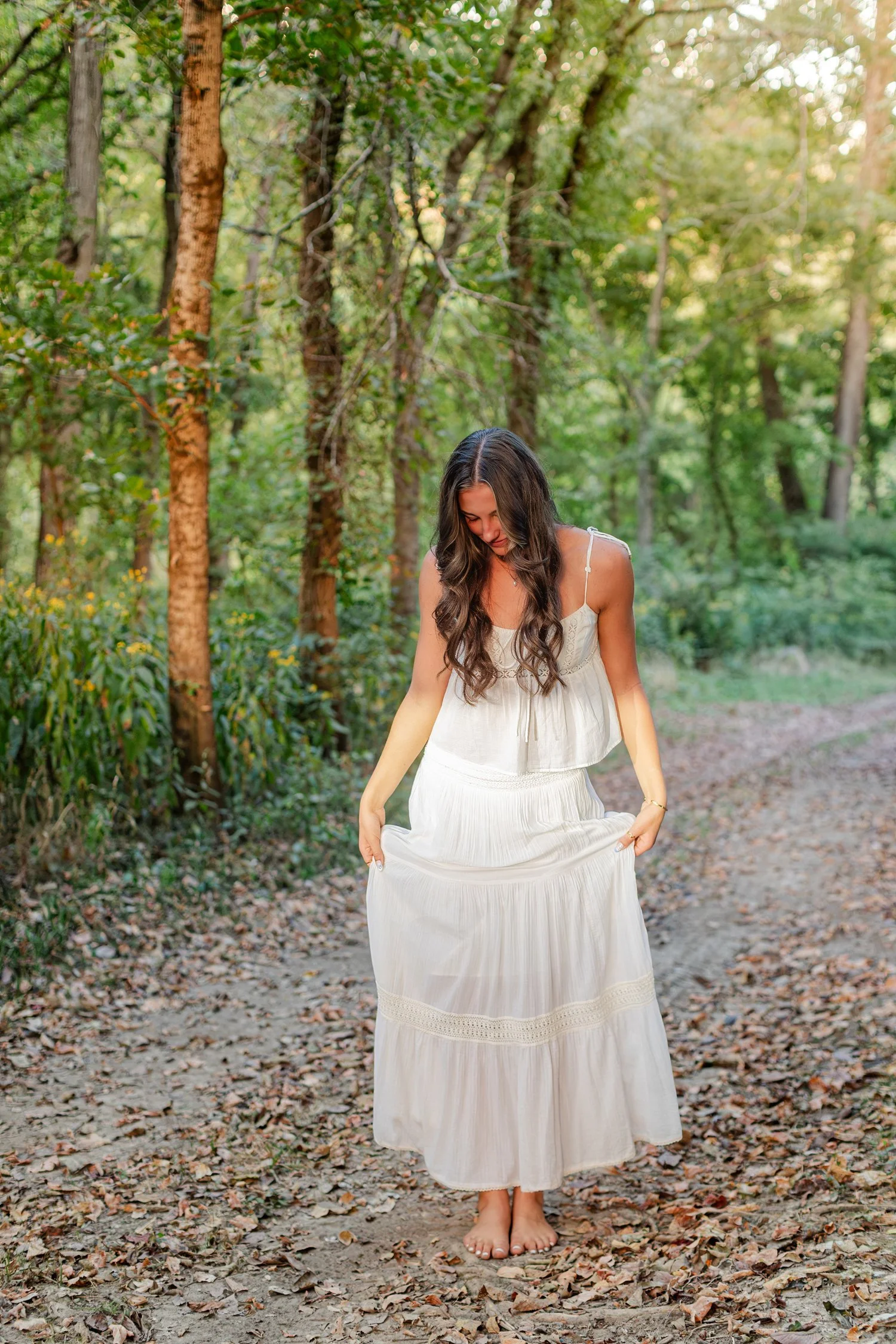 Eisley holding her skirt on a dirt path under the trees, senior pictures near Bolivar, MO