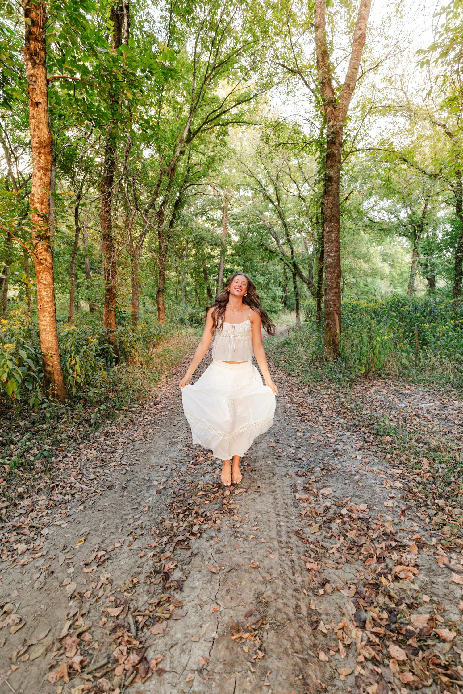 Eisley walking barefoot down a wooded path, senior session near Bolivar, MO