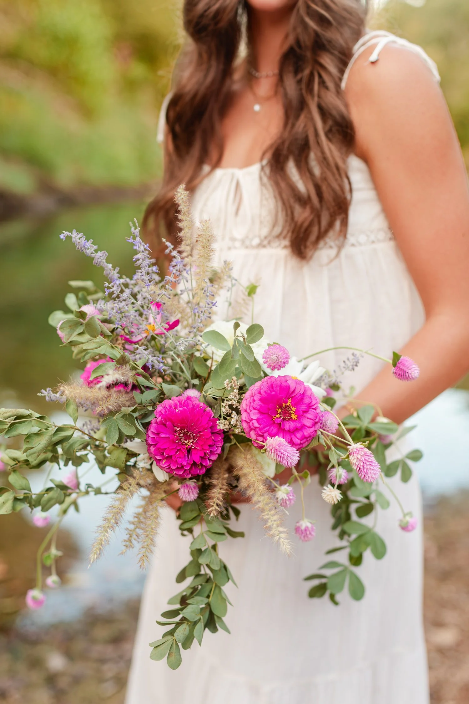 Eisley holding a pink zinnia and wildflower bouquet, senior pictures near Bolivar, MO