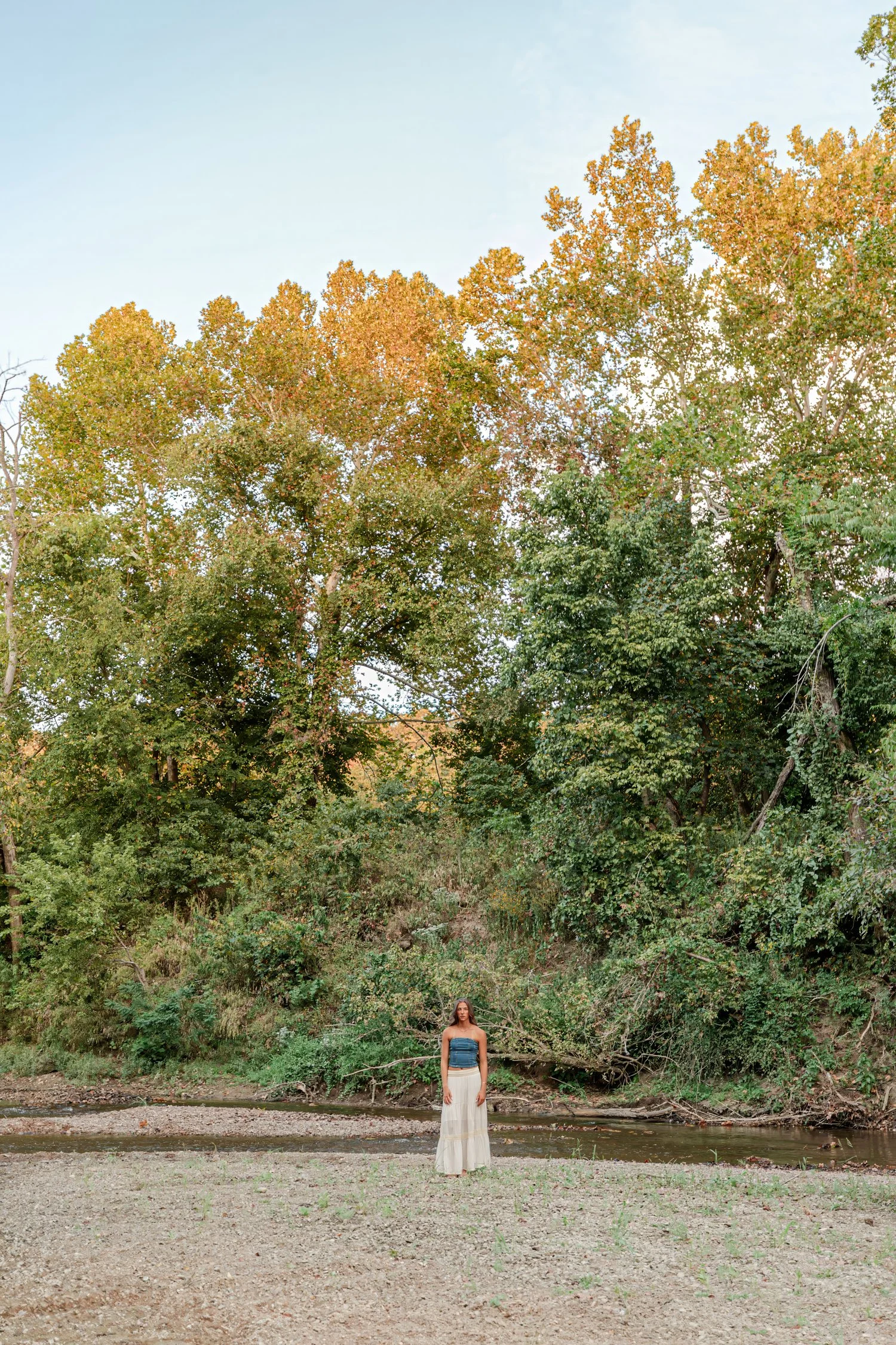 Wide view of Eisley among the trees by the river, senior pictures near Bolivar, MO