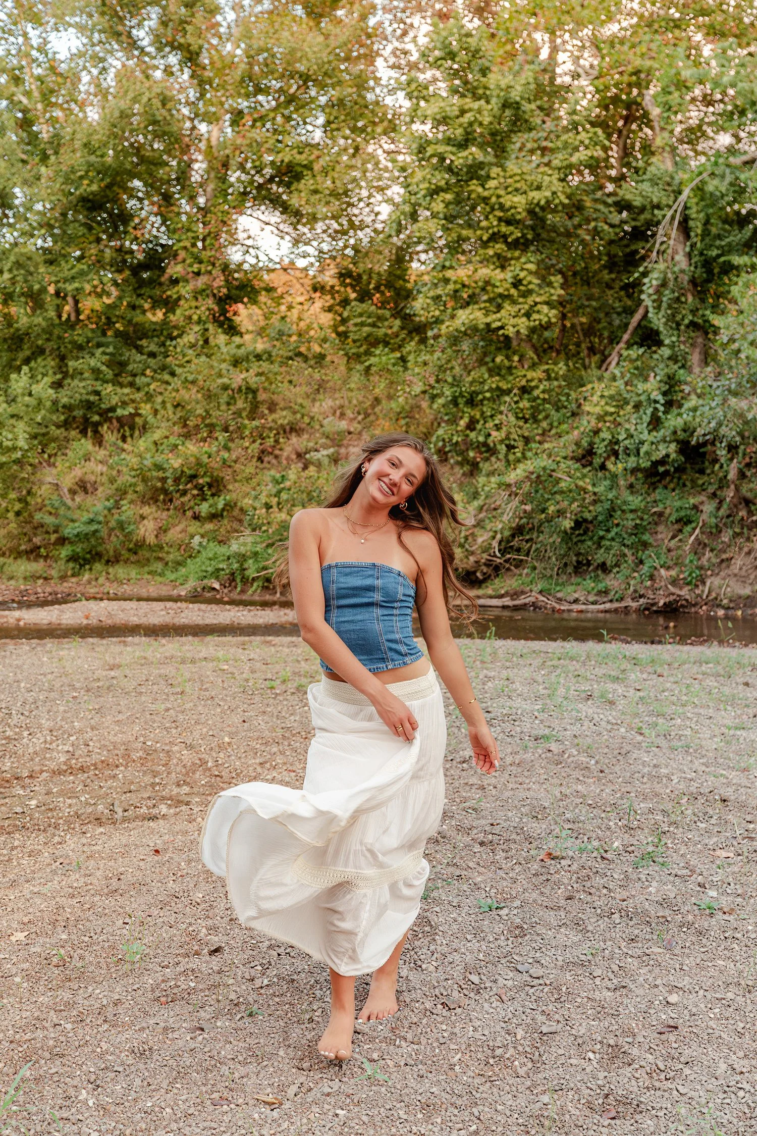Eisley in a denim top twirling her skirt on the gravel bar, senior pictures near Bolivar, MO