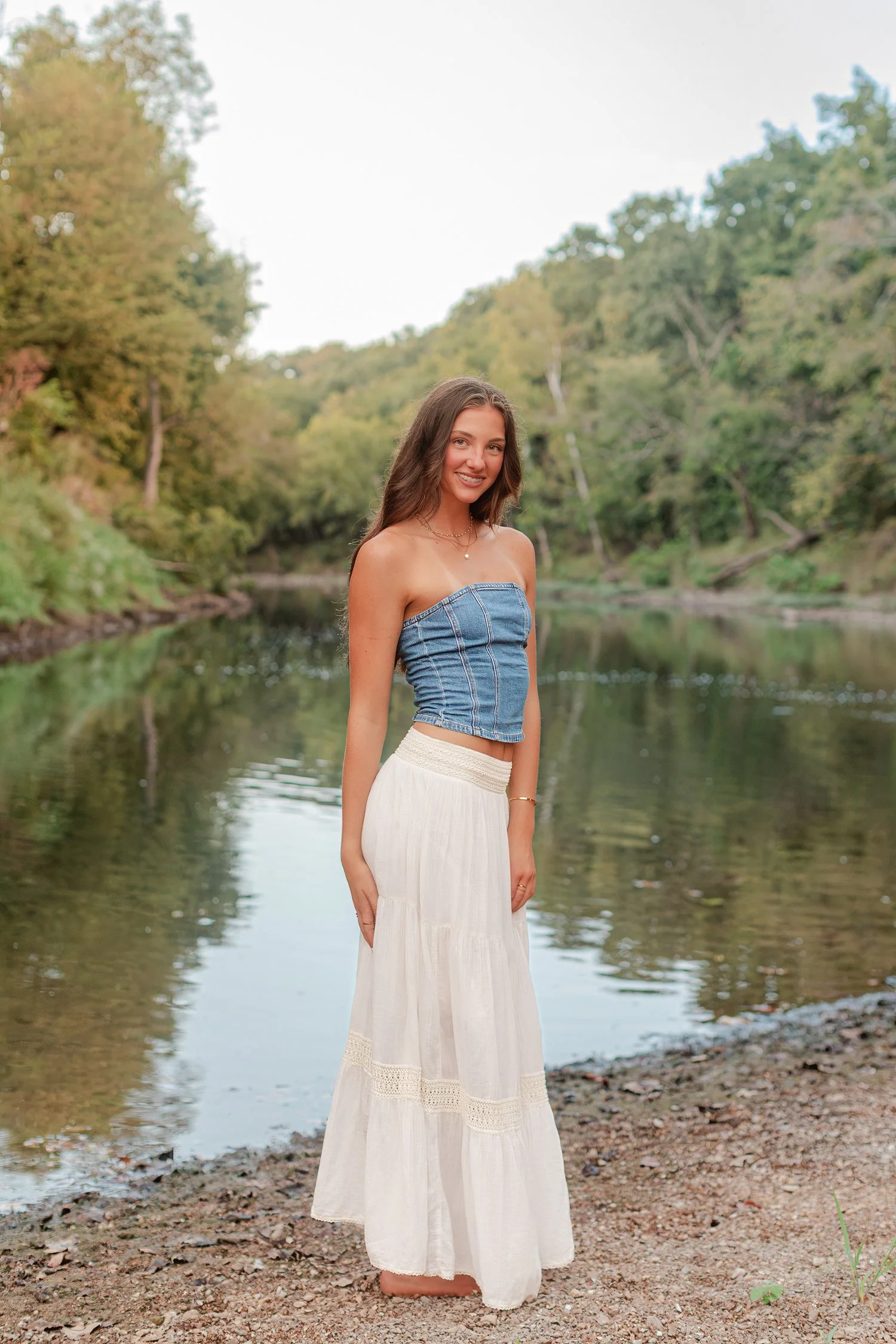 Eisley standing by the river in a denim top, Class of 2027 senior pictures, Bolivar, MO