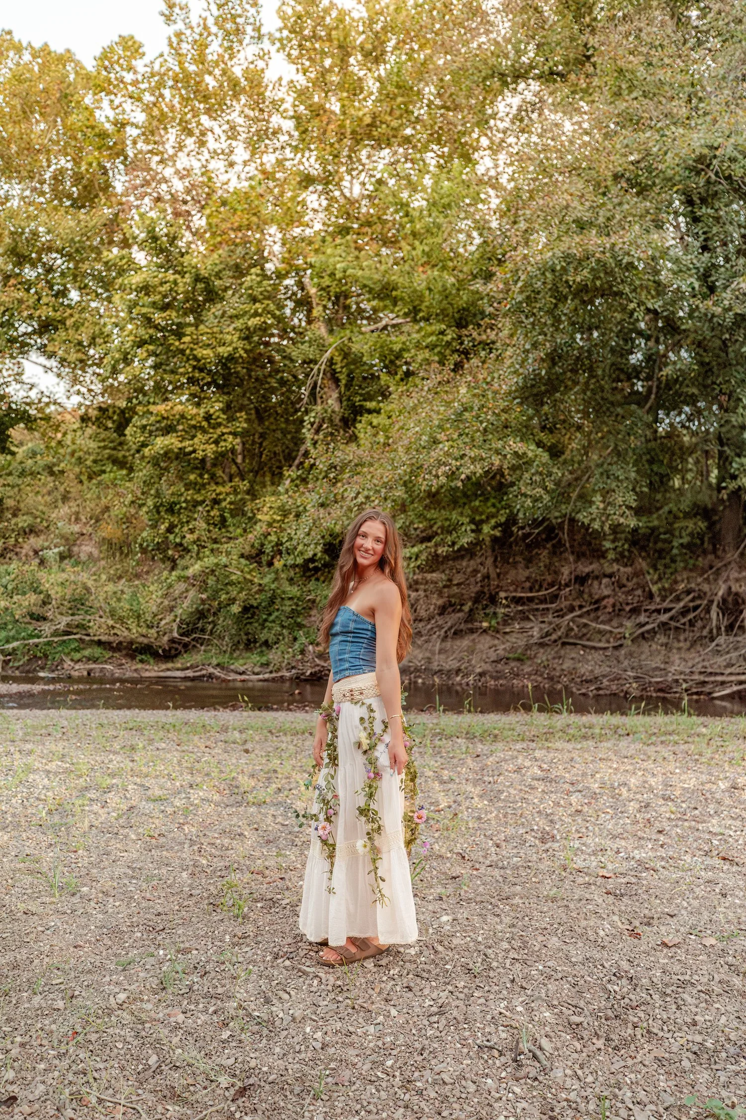 Eisley with a green vine garland on the gravel bar, senior pictures near Bolivar, MO