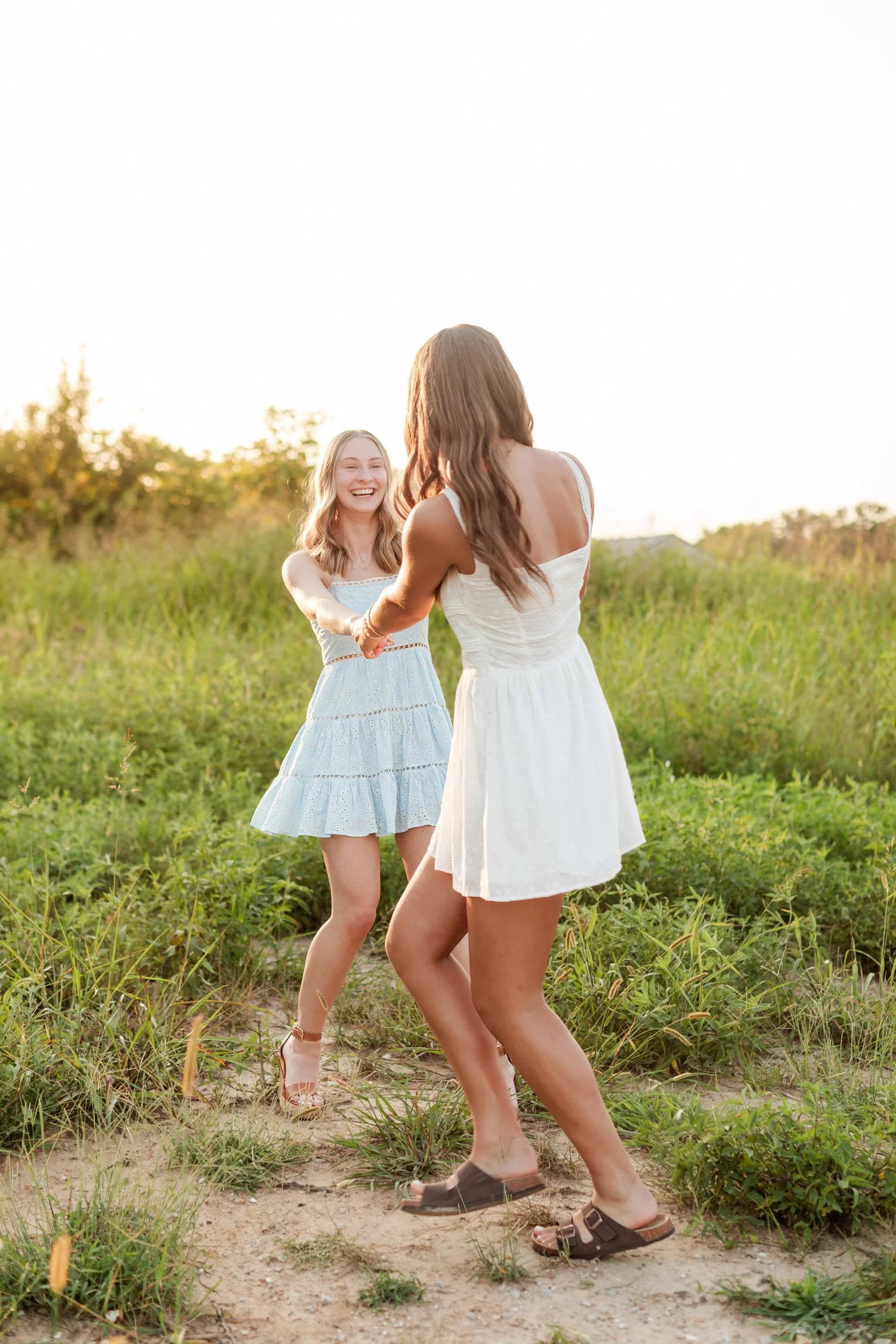 Two seniors dancing face to face on a sandy patch of the field, bestie senior pictures in Bolivar, MO
