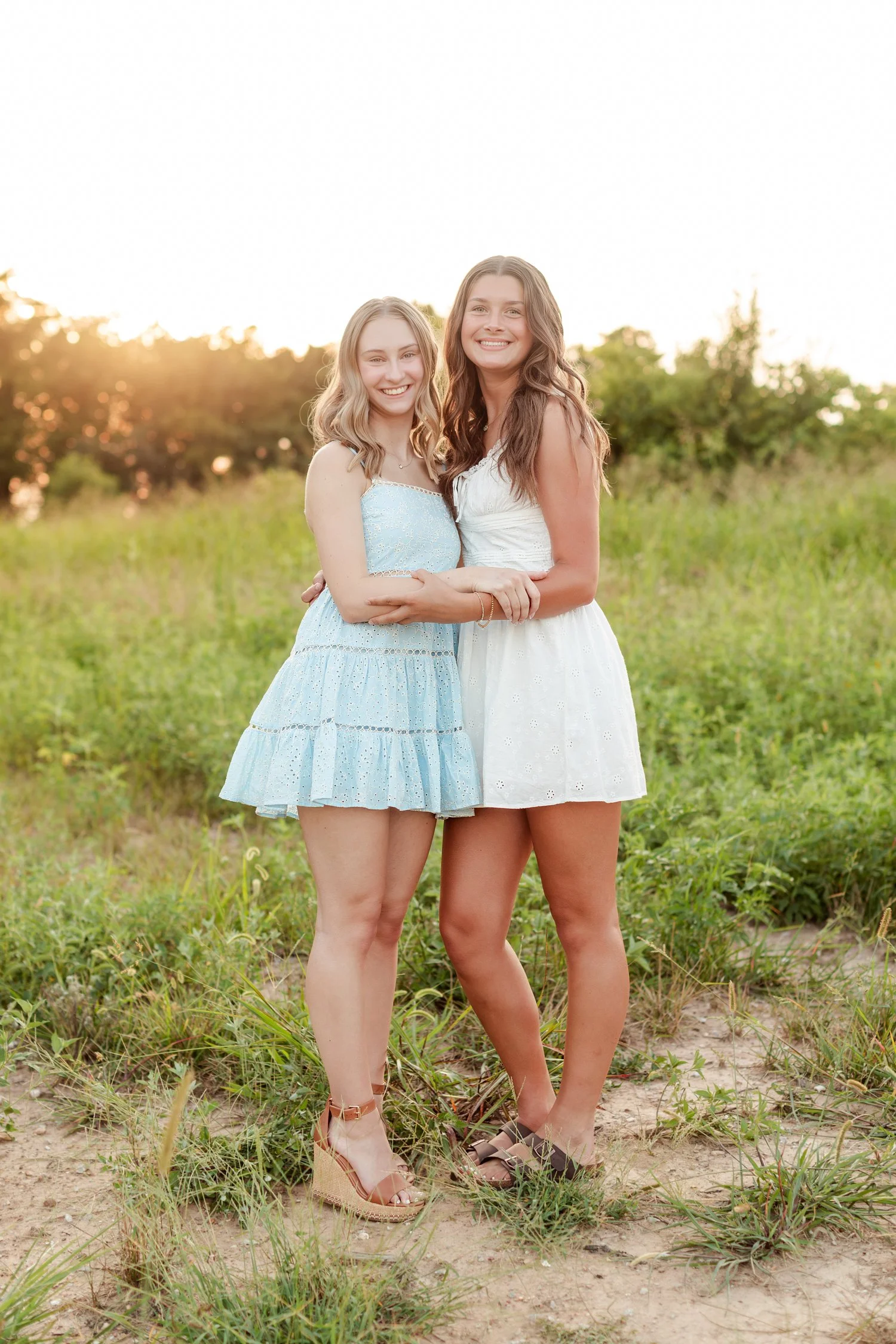 Two seniors hugging side by side and smiling in a grassy field, bestie senior pictures in Bolivar, MO