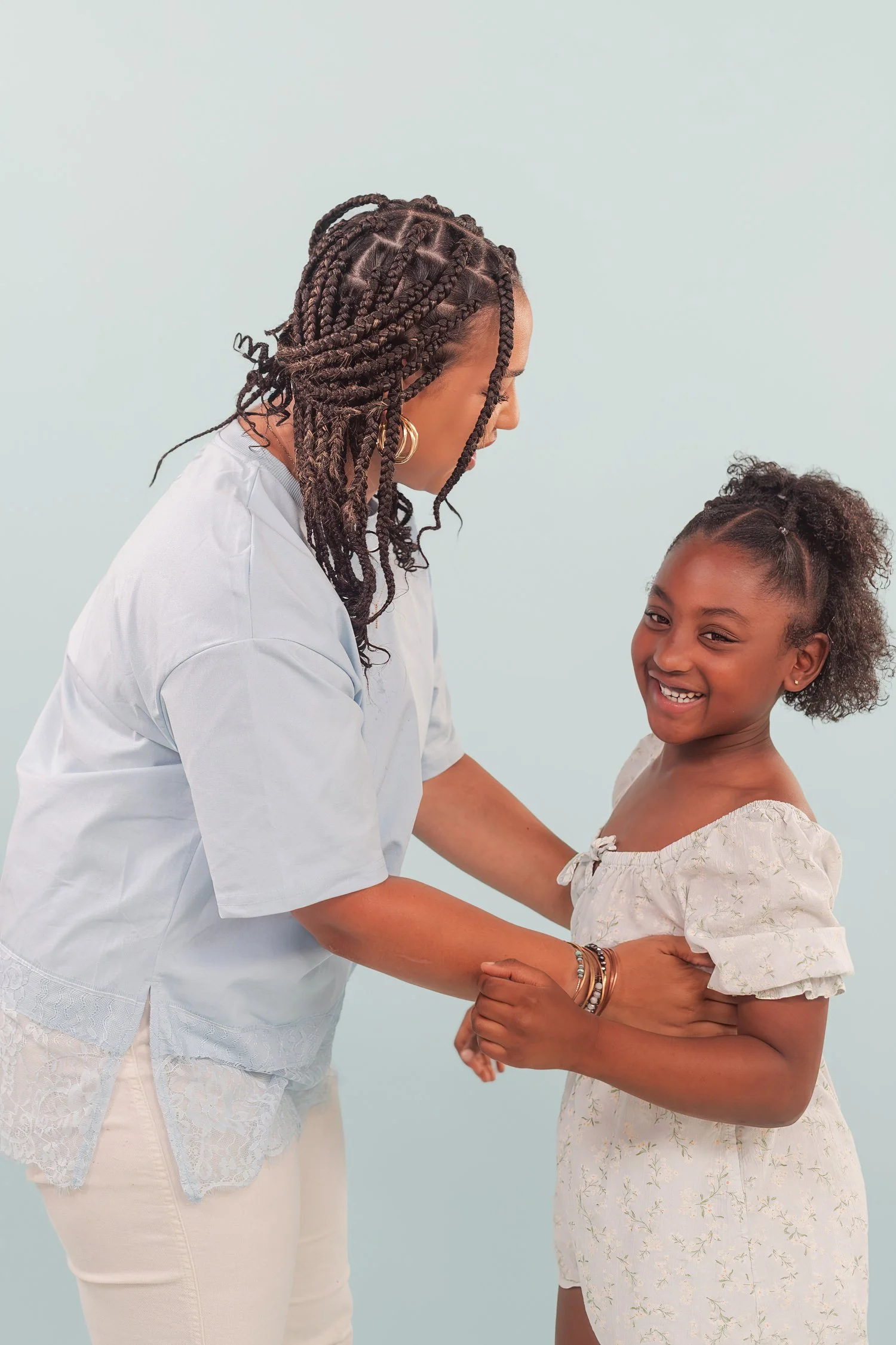 Mother and daughter holding hands and laughing face to face in the studio, mother daughter photos in Bolivar, MO