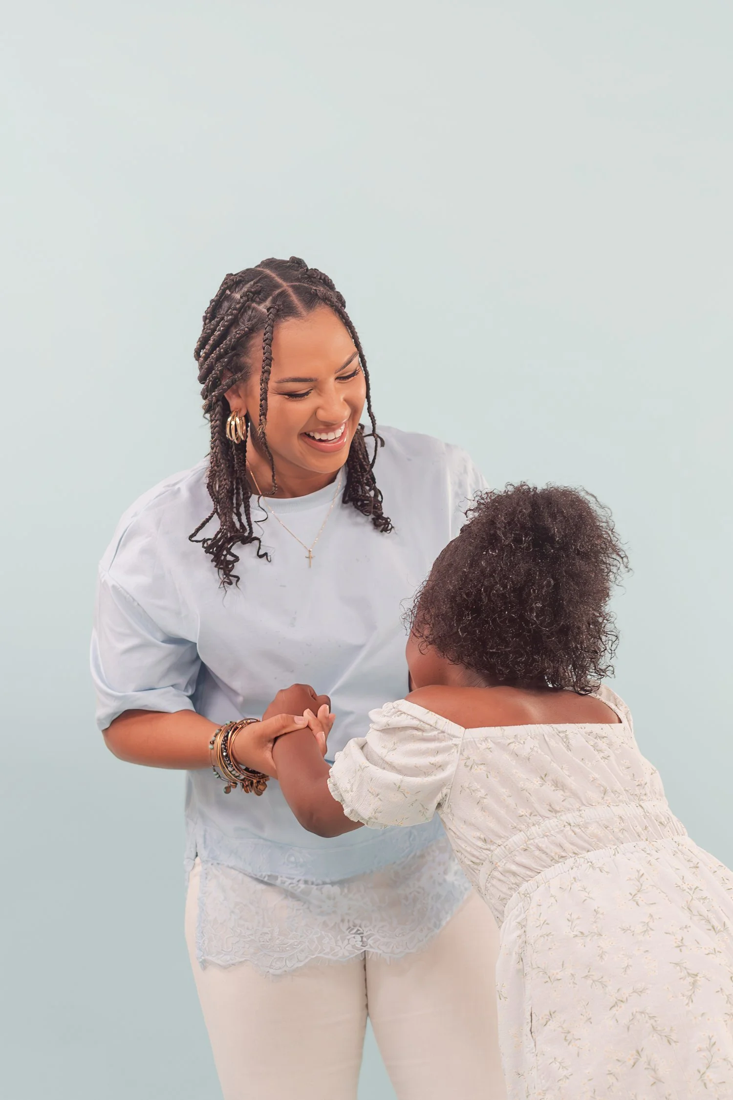 Mother in a light blue shirt spinning a daughter by the hands in the studio, mother daughter photos in Bolivar, MO