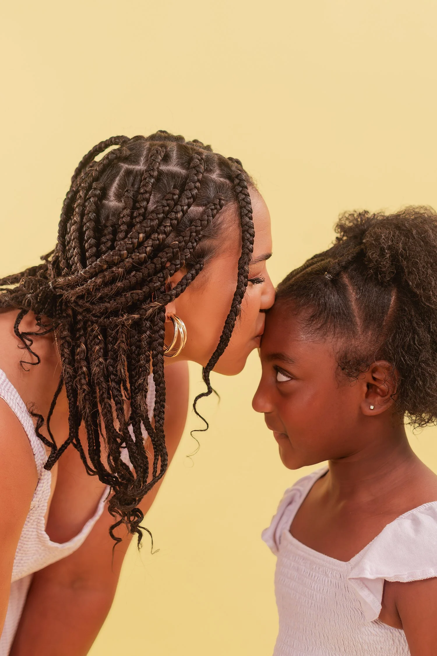 Mother and daughter touching foreheads in profile against a yellow backdrop, mother daughter photos in Bolivar, MO