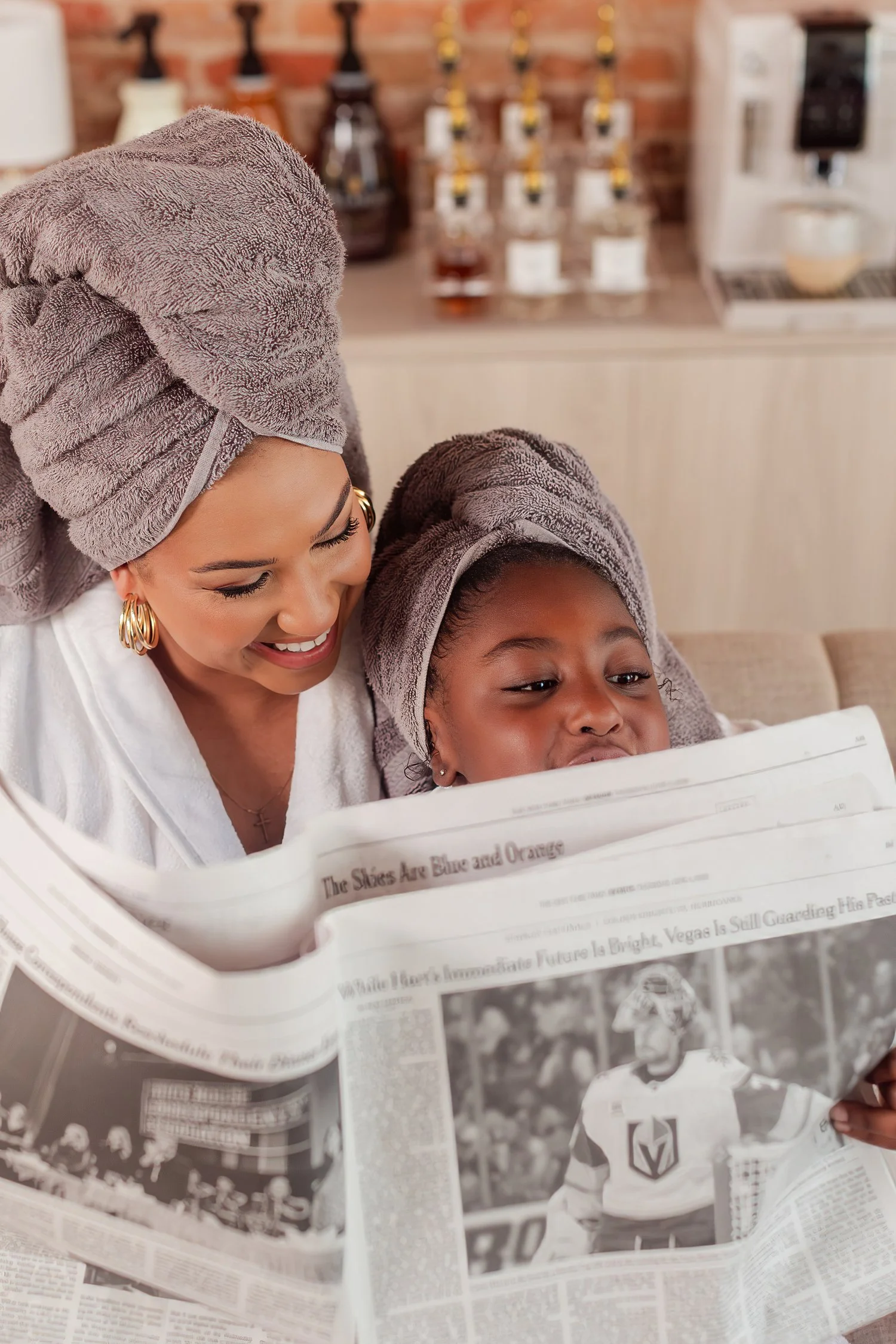 Mother and daughter in towel wraps reading a newspaper together, mother daughter photos in Bolivar, MO