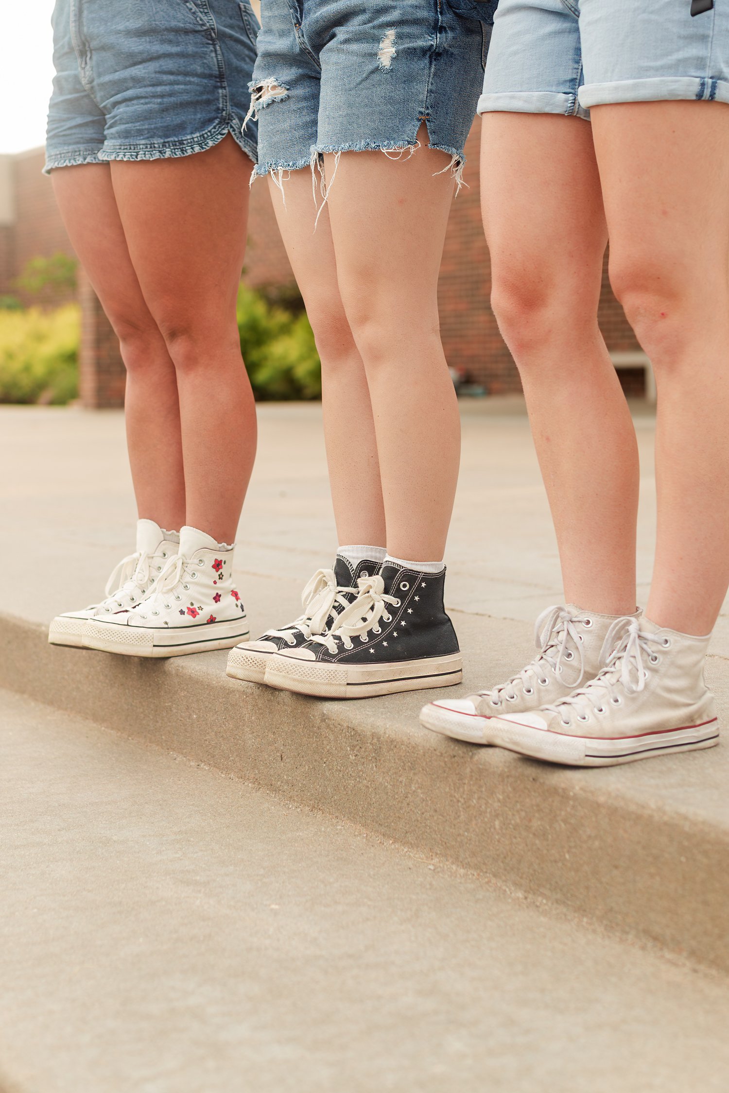 Close view of three friends' denim shorts, socks, and sneakers.