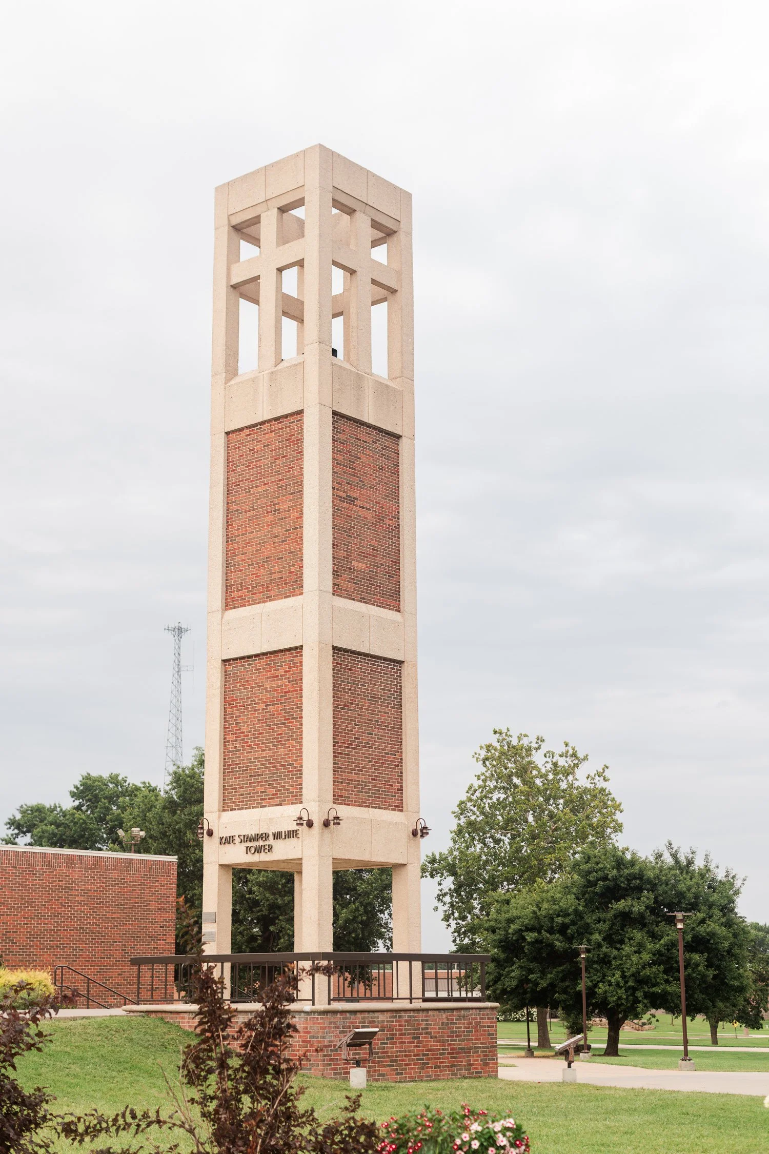 Tall brick bell tower standing above a campus lawn.