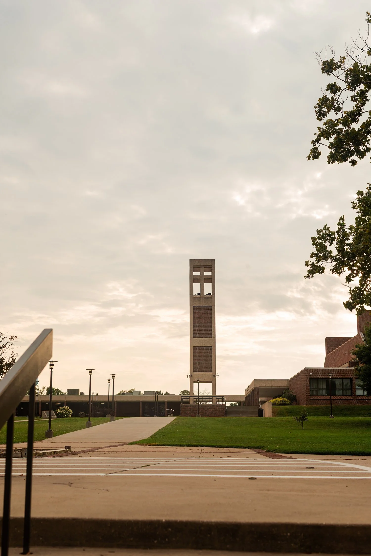 Campus bell tower and buildings beneath a cloudy sky.
